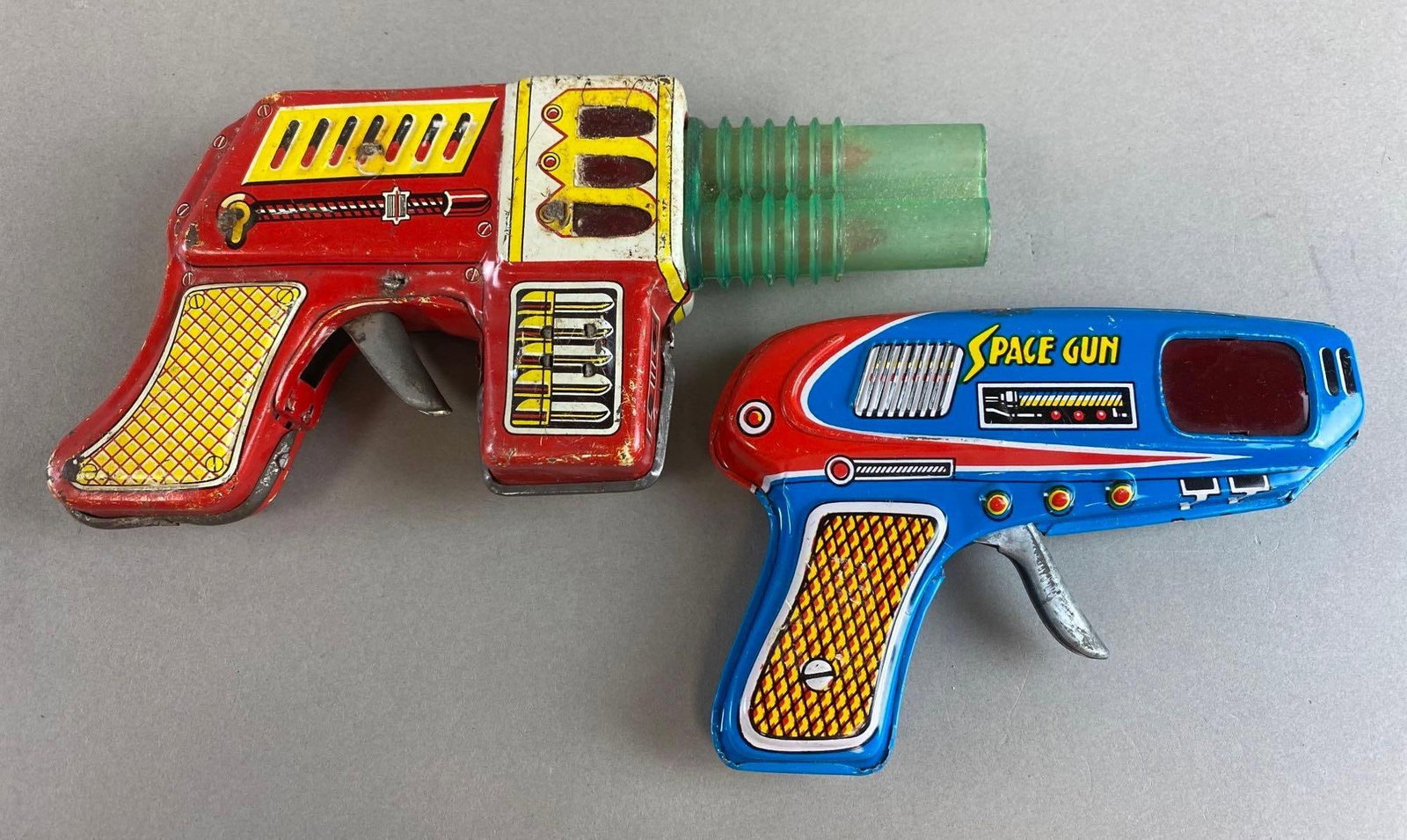 2 Vintage Tin Lithograph Toy Guns Metal Friction: Both work, surface wear and scratches. Largest measures 4 x 8 1/2 x 2 inches. Shudo and Good Toy both made in Japan.