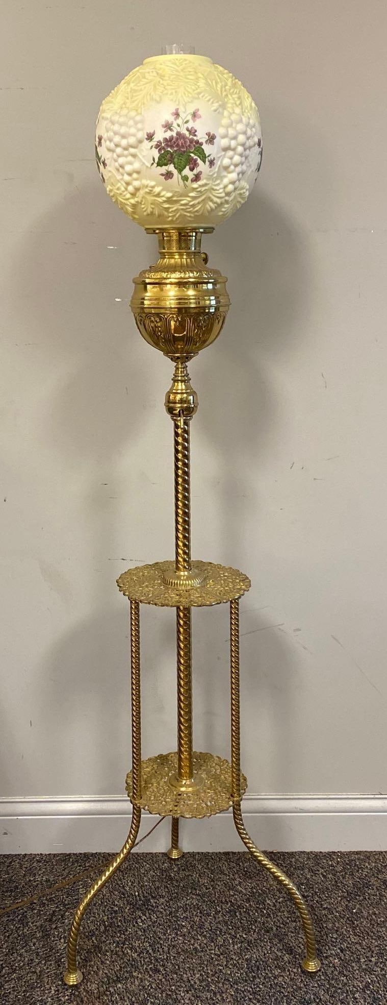 Tall Brass Standing Piano Lamp with Satin Glass Globe: Electrified, In working condition, Globe embossed and painted with grape and vine patterns with wildflowers, Measures 63 x 18 x 18 inches.
