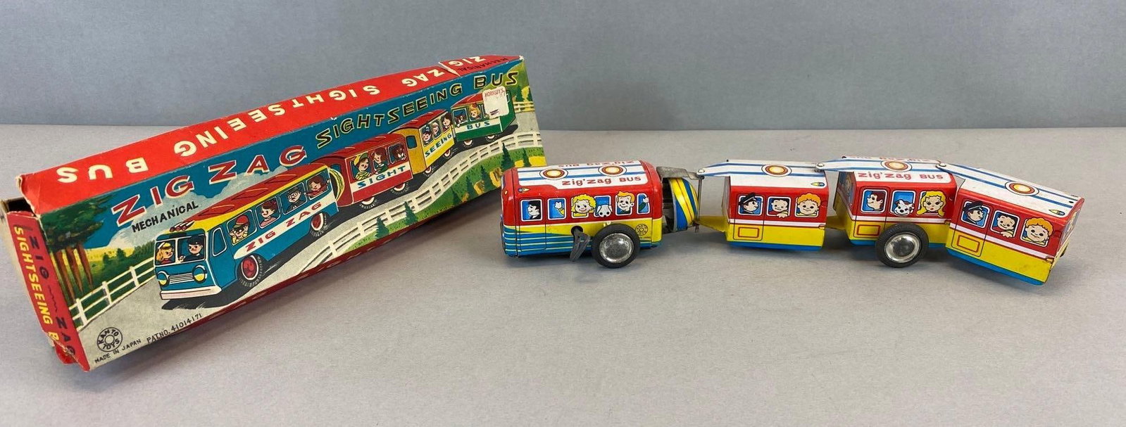Vintage Kanto Toys Tin Litho Zig Zag Bus Windup in Box: Has wear, box has creases and tears, windup works. Measures 2 x 12 x 3 inches.