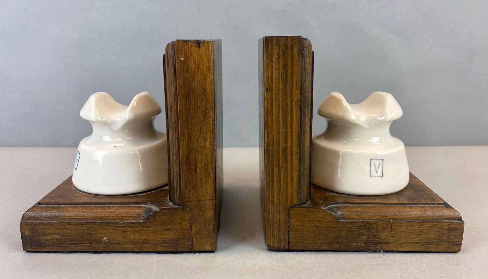 Vintage White Glazed Porcelain Insulator Book Ends: Stained wood bases. Scratch on 1 insulator. Each measure 7 x 5 1/2 x 6 inches.
