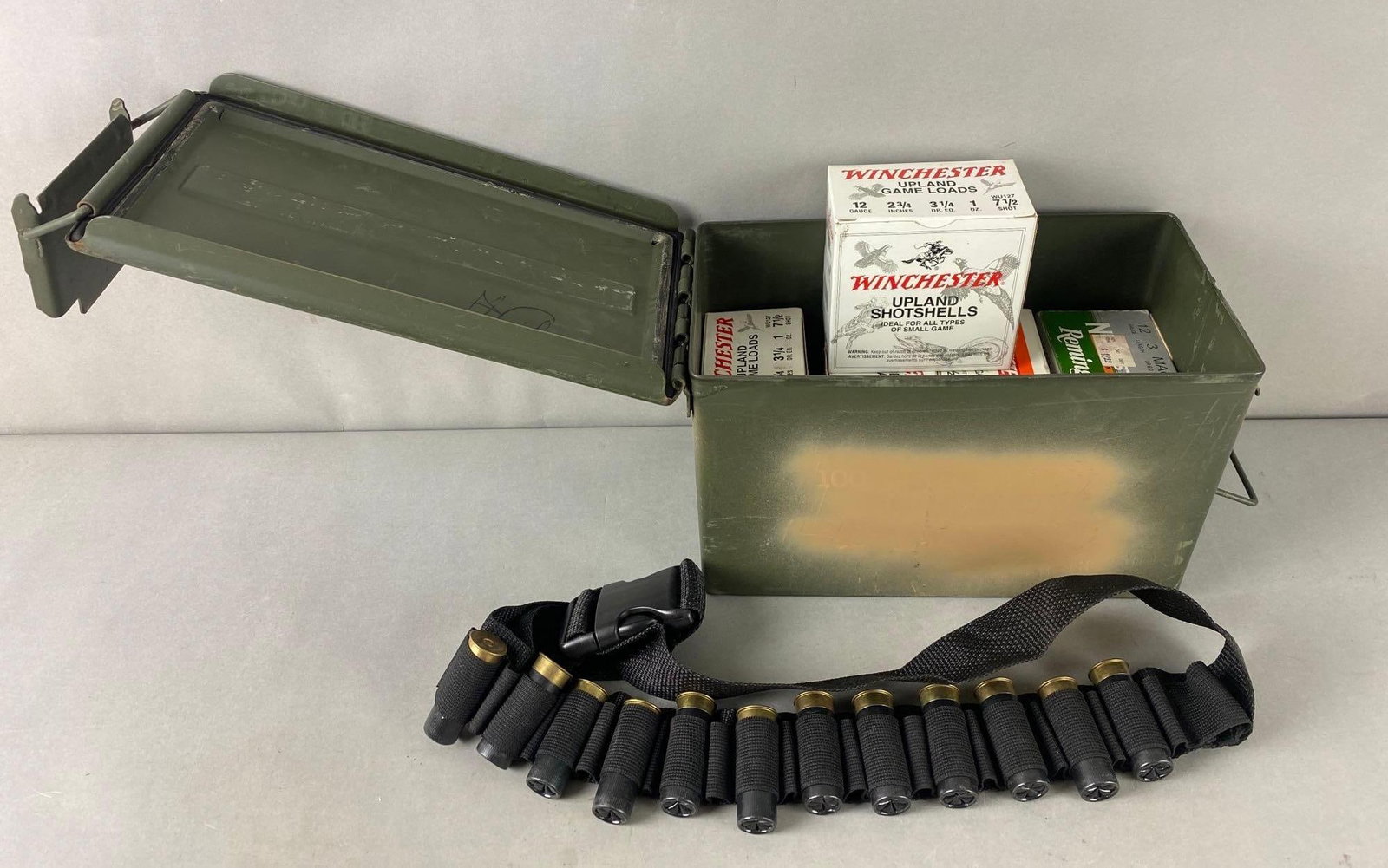 Metal Ammunition Box w/ 12 Gauge Shells in Boxes and Bandolier: 4 Full Winchester boxes and 1 partial Remington. Also holder belt with shells. Box has wear and rust. Box measures 7 1/2 x 12 x 6 inches.