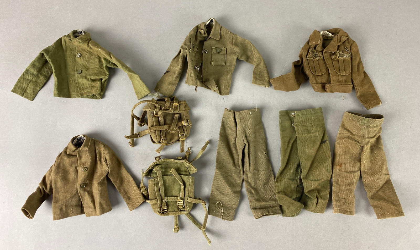 Group of Hasbro G I Joe Military Uniform Accessories: Total of 9 items. Includes pants, jacket, backpacks and more. Mixed condition. Pants are 6 inches long.