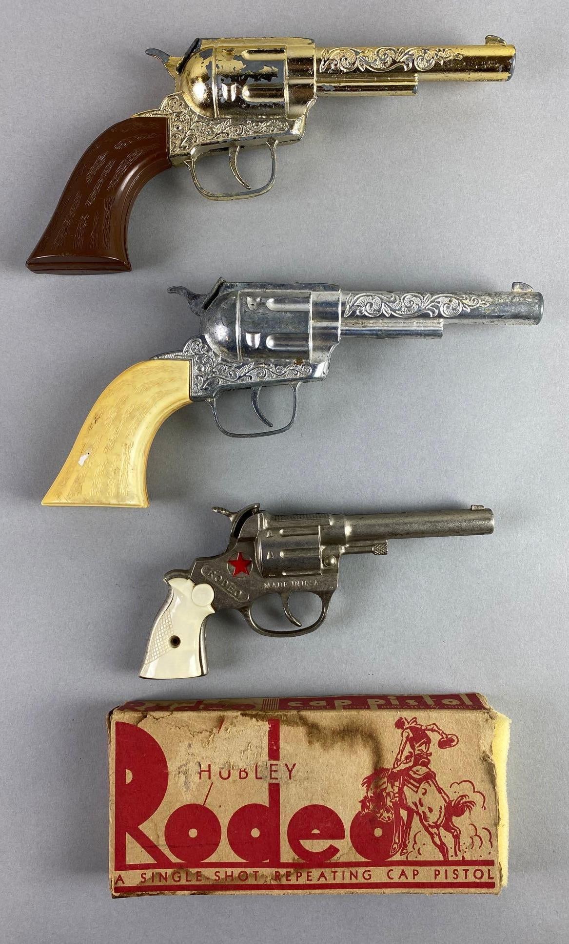 Group of 3 Hubley Cap Guns: Includes 1955-65 Rodeo with original box and 2 1970 Pony Boy, in working condition, 1 grip is cracked and loose, 1 loose cap cover, largest measures 9 1/2 x 4 1/4 x 1 1/4 inches