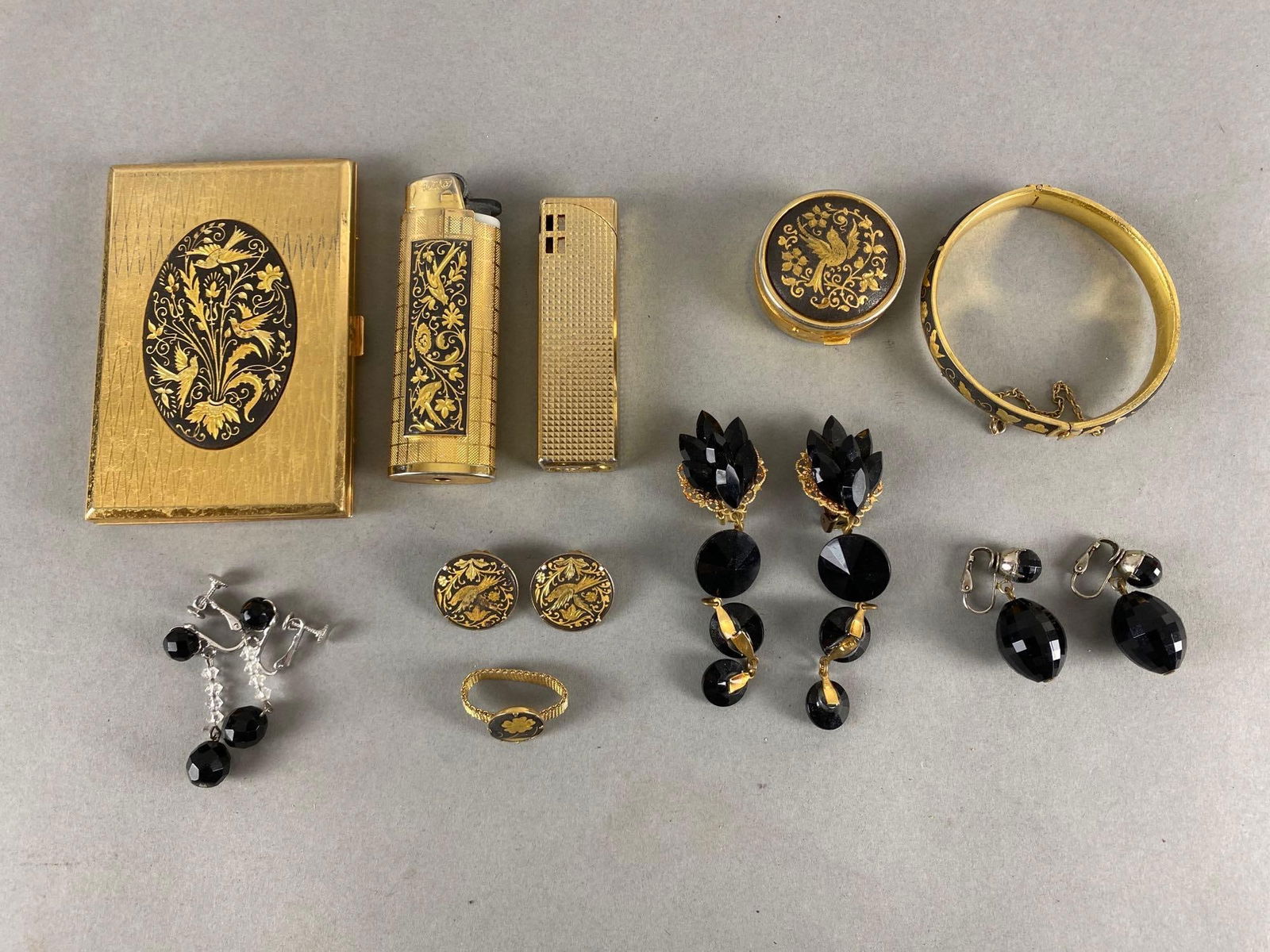 Group of 10 Assorted Costume Jewelry Items and More: Includes lighters, clip-on earrings, pill box, and more, Cigarette case measures 3 3/4 x 2 1/2 inches.