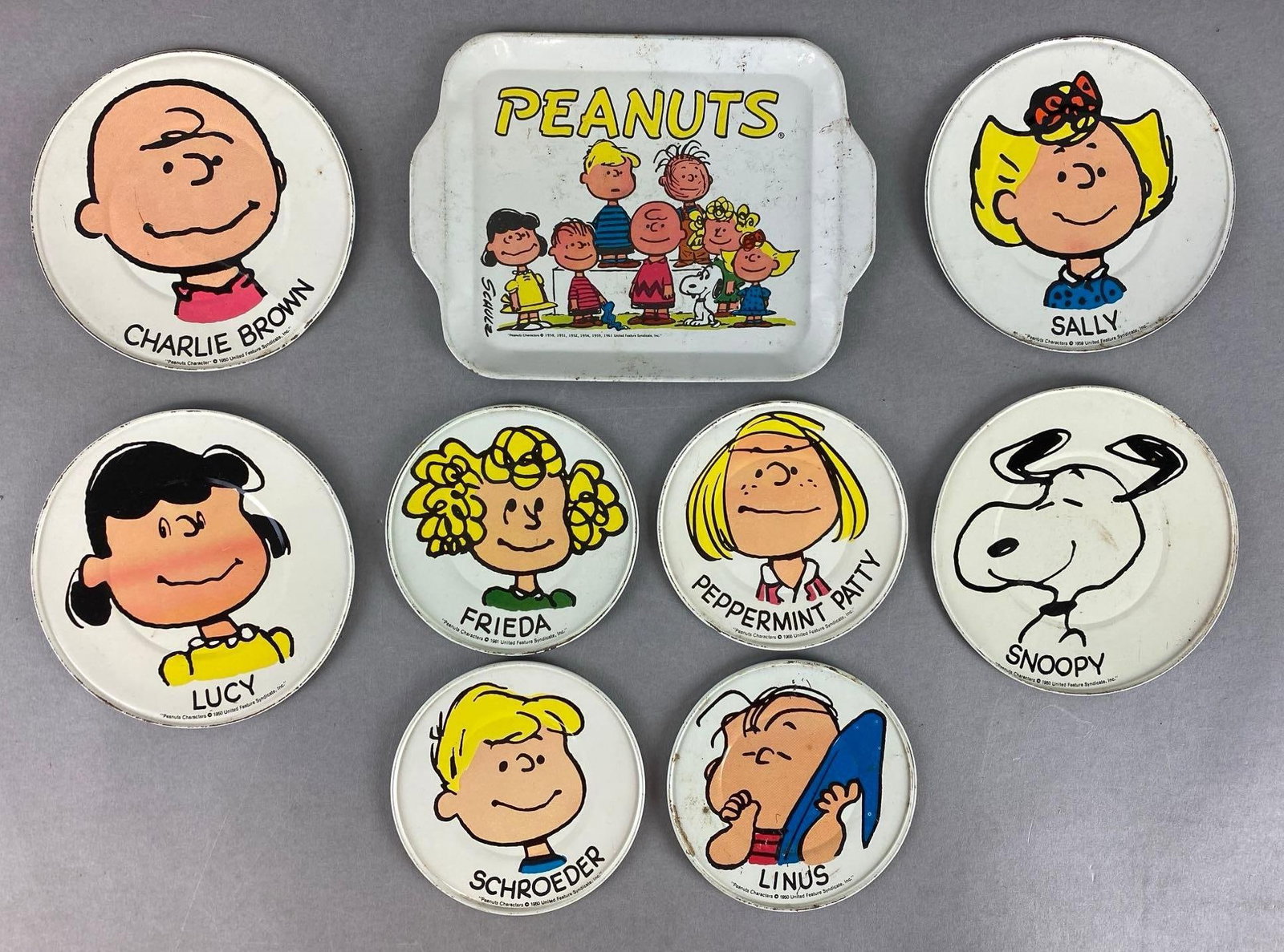 Group of 9 Charlie Brown Tin Plates: Unknown set completion, discoloration throughout, largest measures 7 1/2 x 5 1/2 inches