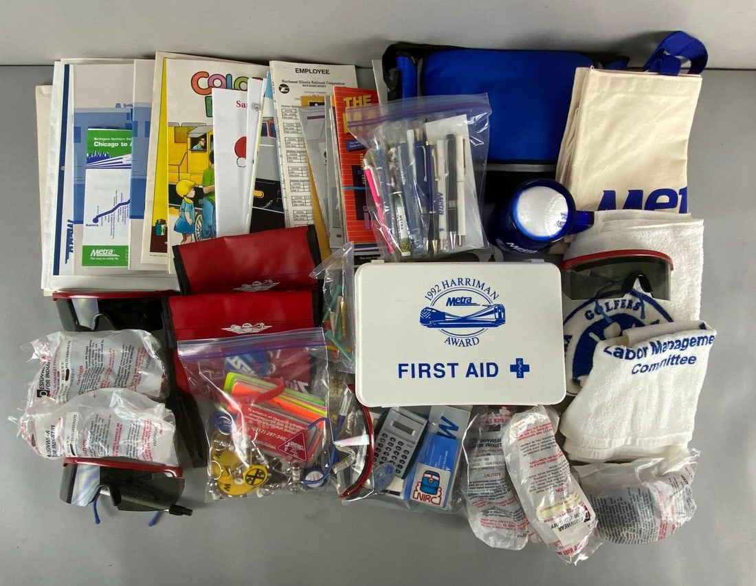 Large Group of Assorted Metra Railroad Items and More: Includes First Aid Kit, Safety glasses, Keychains, Ephemera, and more, First Aid Kit measures 7 x 10 x 3 1/4 inches.