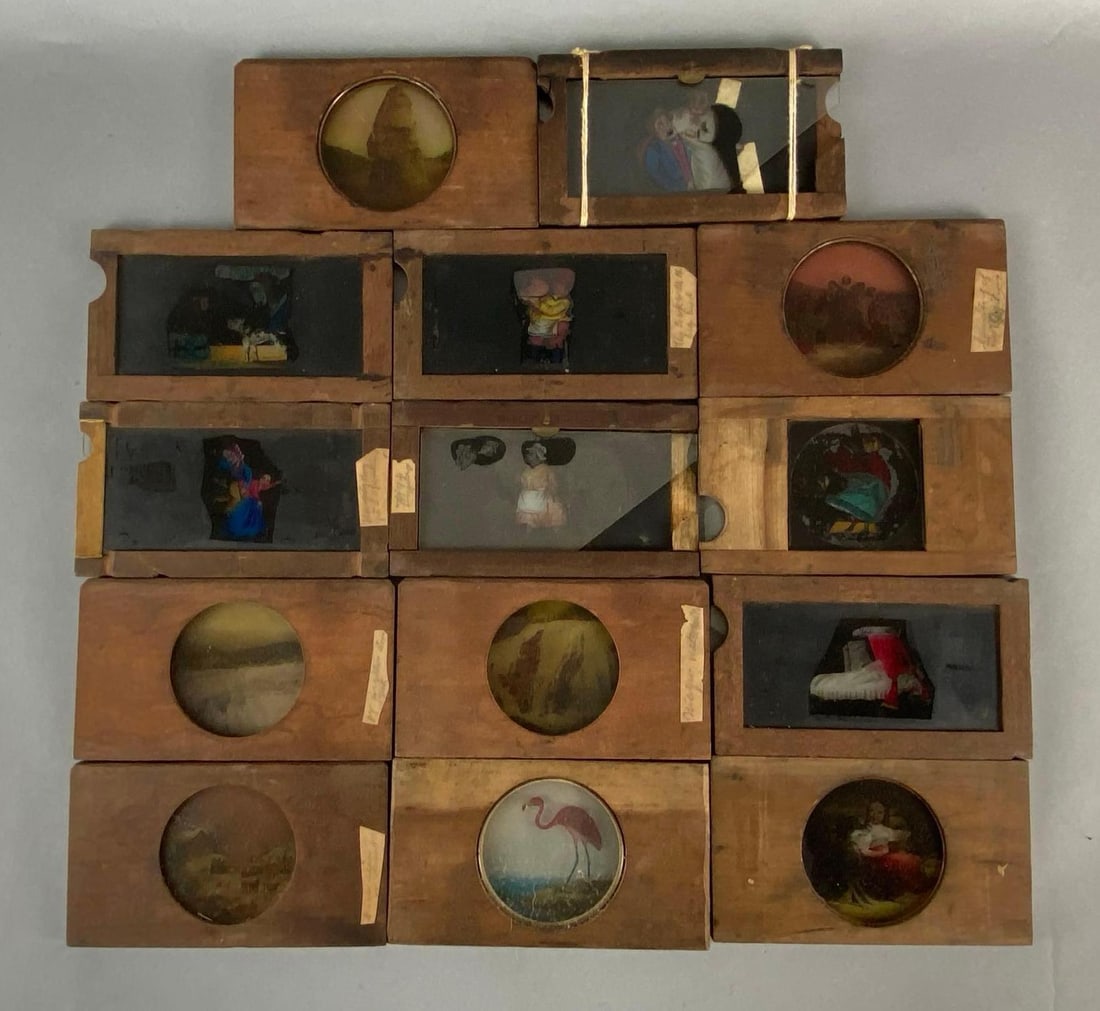 Group of 14 Antique Magic Lantern Colored Glass Slides: Some with movement components, Includes characters, nature, religious scenes, and more, Some cracks or broken pieces, Frames measure 4 x 7 inches.