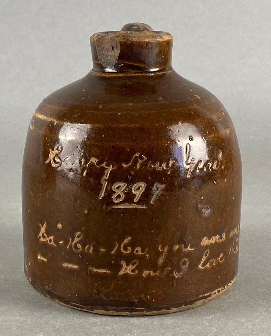 1897 New York Personalized Brown Glaze Stoneware Jug: Marked La-La-La You and Me, How I Love Thee, Some large chips along rim, Measures 5 1/2 x 5 x 4 1/2 inches.