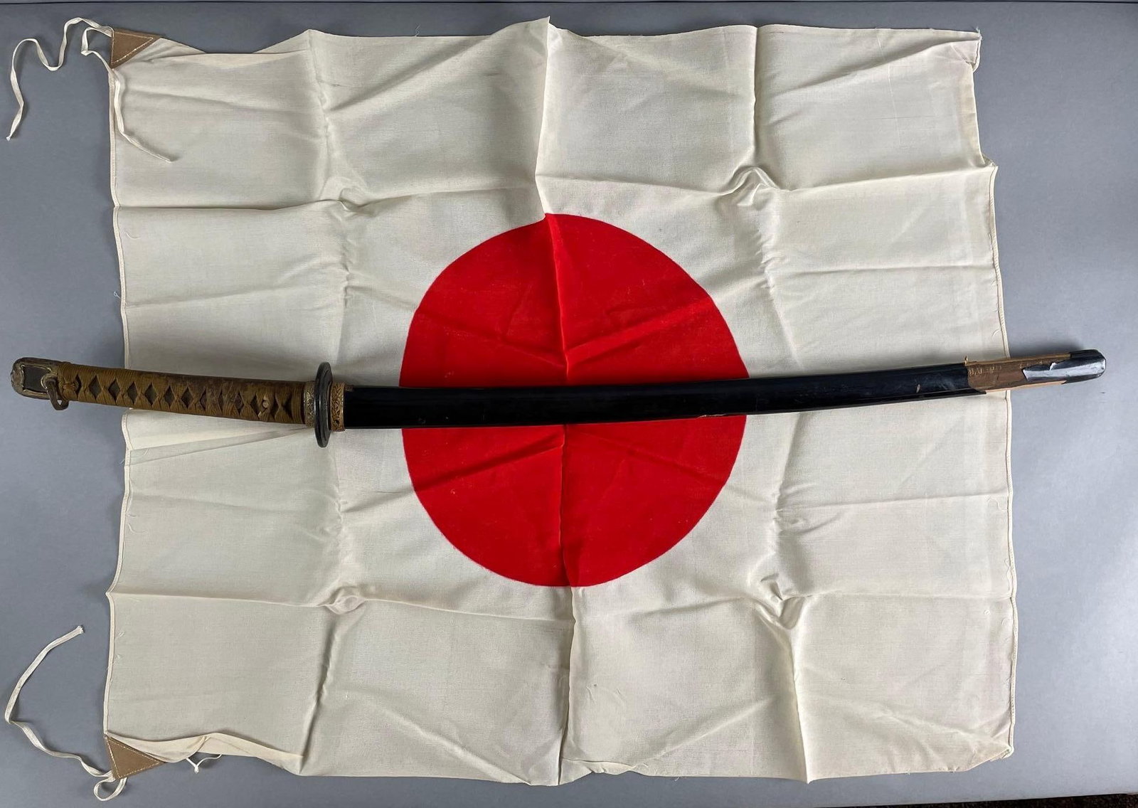 WW2 Era Japanese Katana Sword with Scabbard and Japanese Flag: Signed on tang, sheath split at end. Measures 36 1/4 inches with a 26 inch blade. Flag measures 29 x 33 1/2 inches