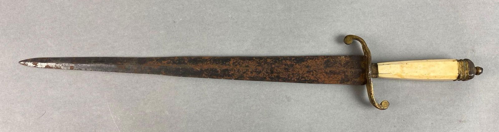 Double-Sided Dagger With Brass Guard and Hilt: Rusting throughout blade, engraving throughout blade, no signifying marks, handle fittings need re tightened, blade length measures 14 inches, total length measures 18 3/4 inches