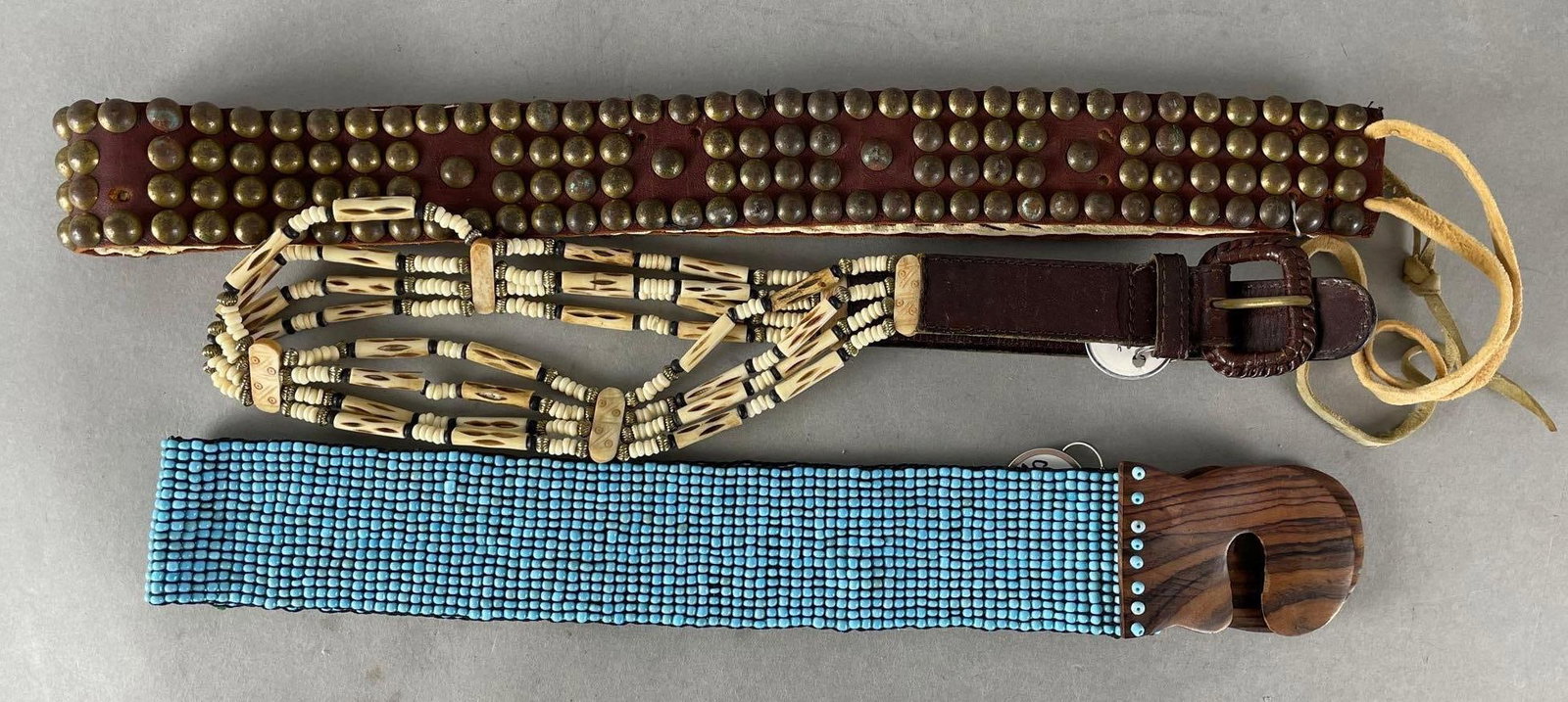 Group of 3 Western Style Belts: Includes bone and leather, leather studded with replaced backing, beaded stretch belt. Longest measures 36 1/2 inches