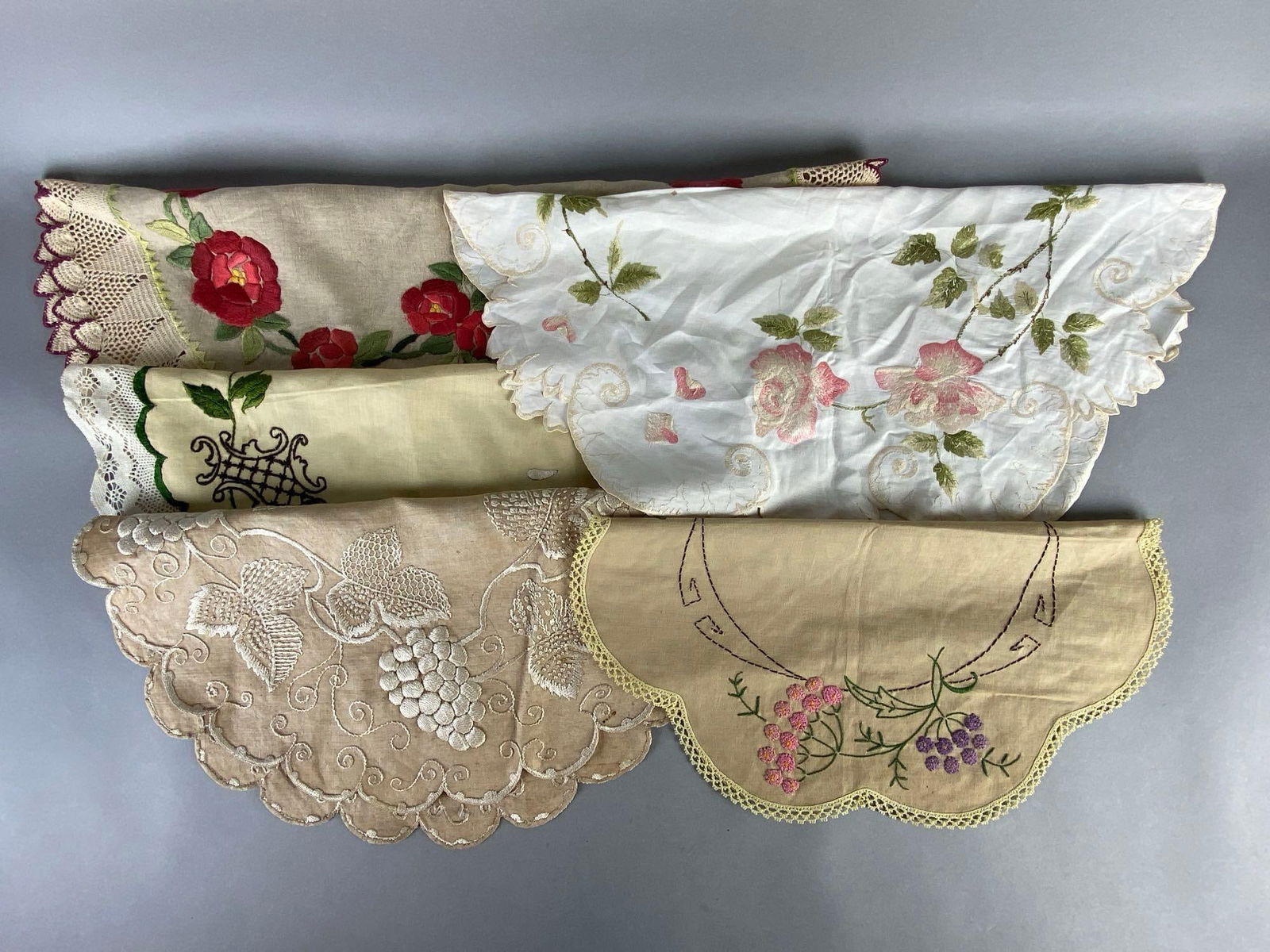 Group of 5 Lace and Embroidered Table Centerpiece Doilies: Includes florals, grape and cable, and more, Some small stains, Most round shaped, Largest measures 29 x 29 inches.
