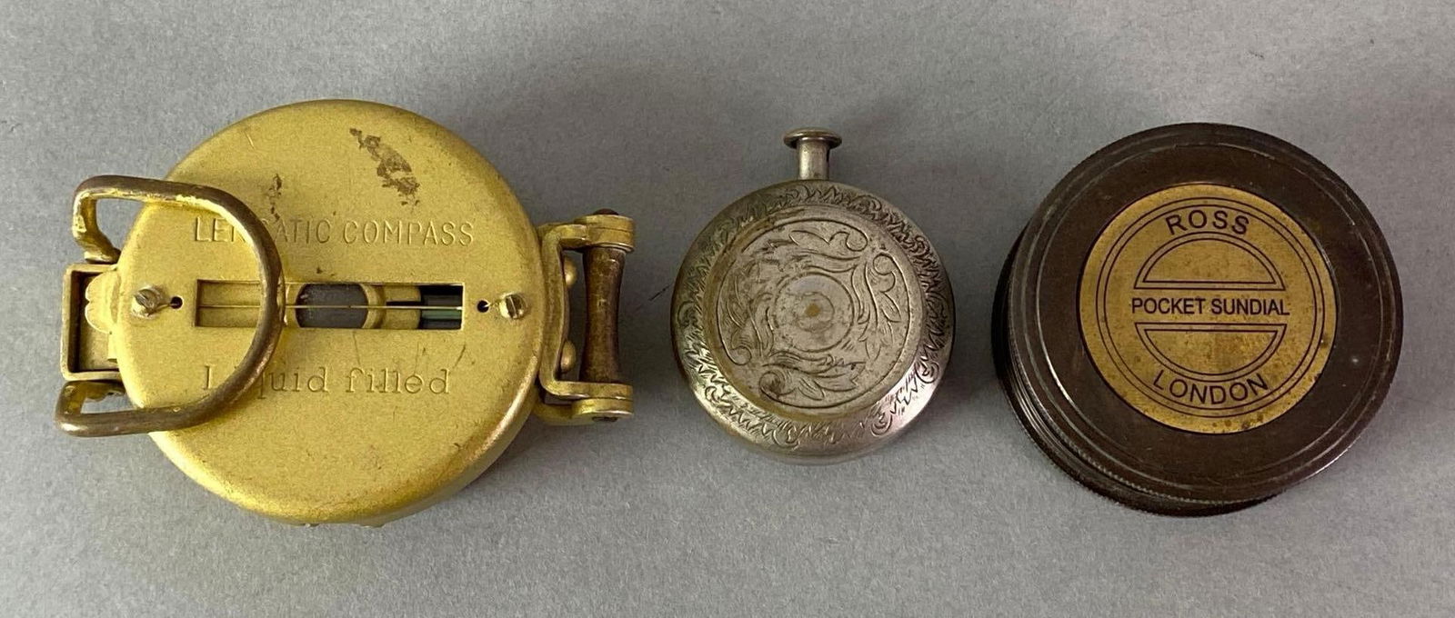 Group of 3 Pocket Compasses and Sundials: Includes Ross London Pocket Sundial, Lenstastic Compass, and unmarked, Largest measures 3 x 2 1/4 x 1 1/2 inches.