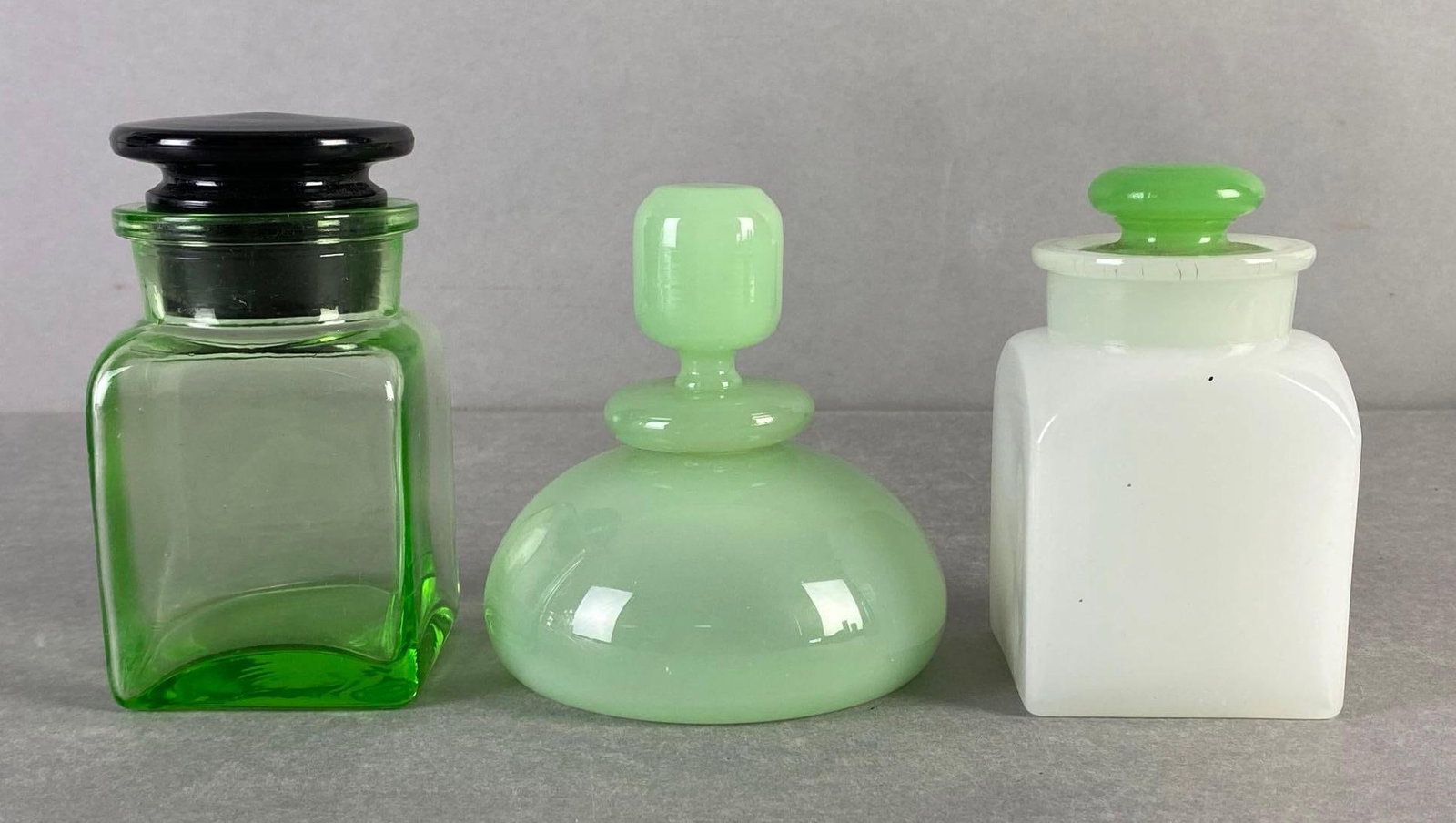 Group of Perfume Bottles: Includes uranium glass, jadeite, and milk glass with green glass stopper, Some fleabites around rims, Tallest measures 4 3/4 x 2 1/2 x 2 1/2 inches.