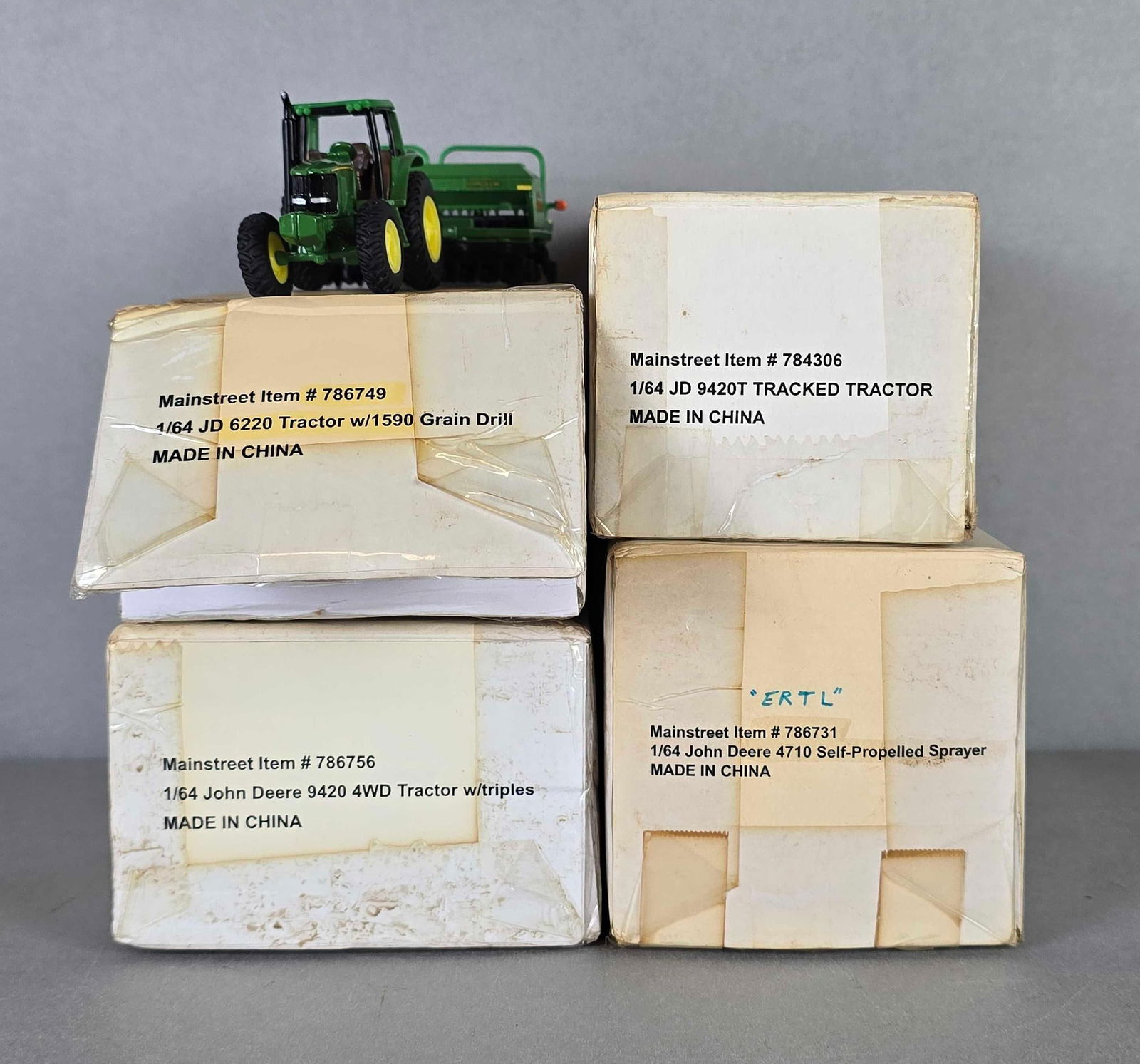 Group of 4 ERTL Die-Cast John Deere Heavy Equipment Vehicles: 1 / 64 scale, sealed in orig8nal boxes, includes tractor with grain drill, tractor with triples, tracked tractor and Self propelled sprayer