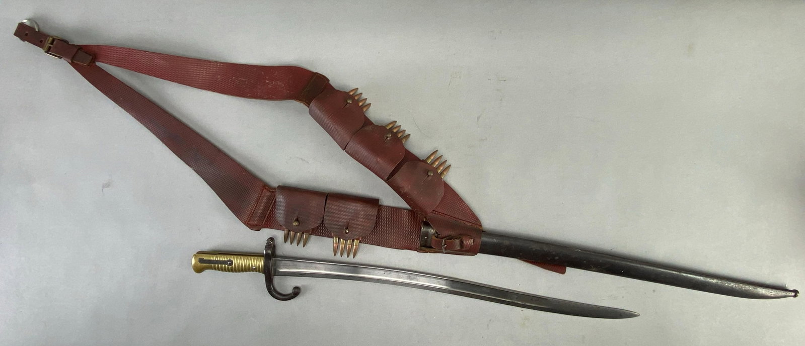 French Leather Bandolier with Ammunition Clips and Bayonet: Includes 20 Rounds of .30 Cal. ammunition stored between 5 clips, each housing 4 rounds and a French Lebel Rifle Bayonet from 1869 with scabbard, bayonet measures 27 1/2 inches in length with a 22 1/2