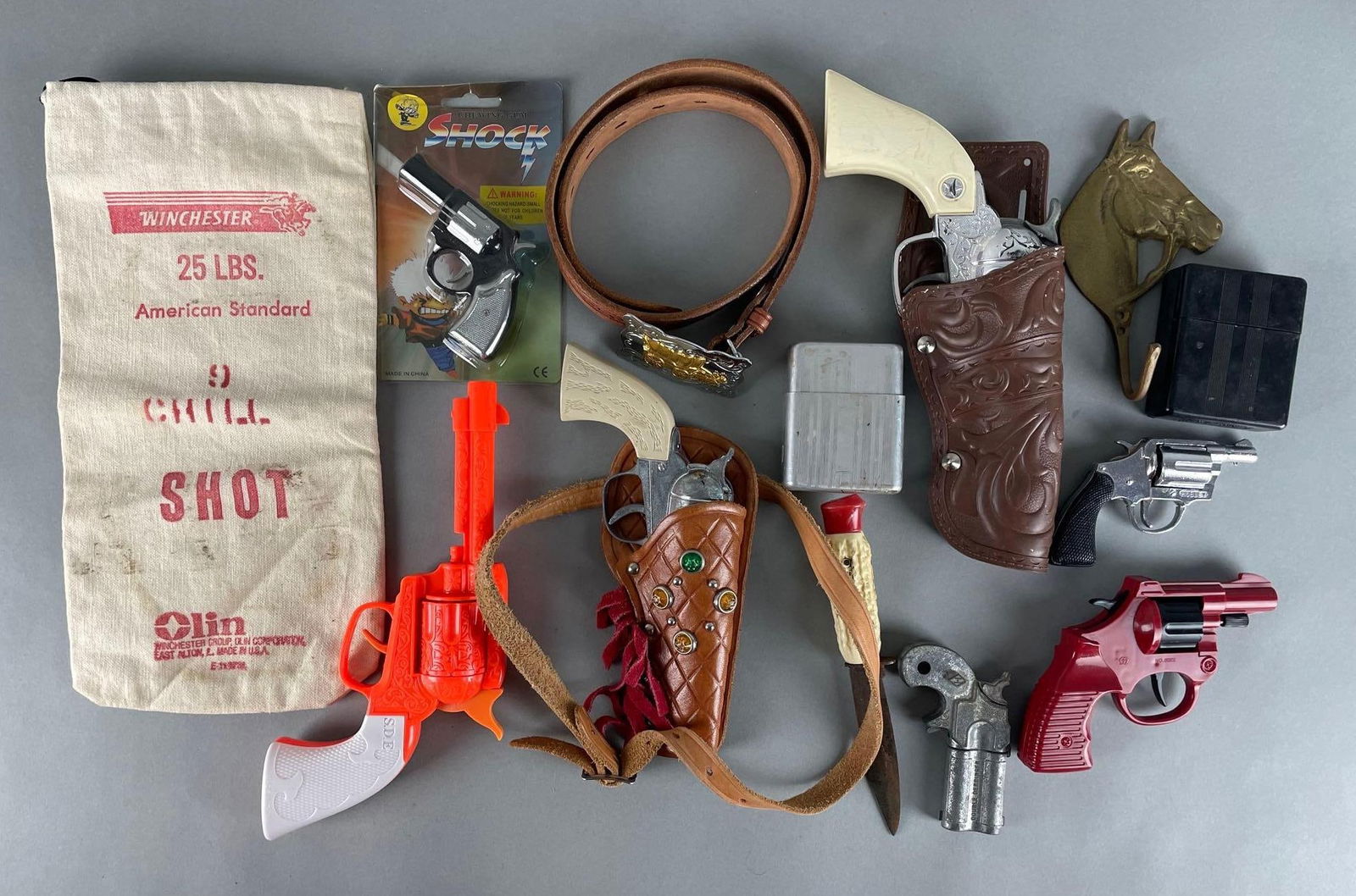 Group of Cap Guns and More: Includes plastic stag handle knife, holsters , brass horse wall hook, and more. Winchester bag measures 12 1/2 x 6 1/4 inches