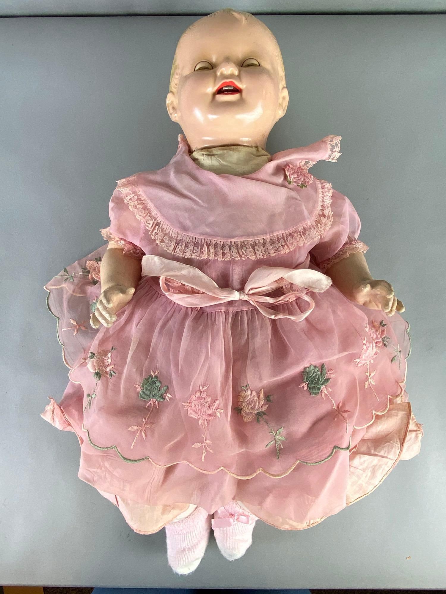 Large Antique Composite Head Baby Doll: 26 inches tall, Circa 1930s, Possibly baby Shirley Temple doll, Unmarked, Composite head and limbs, Cloth body, Cries when turned, Green sleep eyes, 4 teeth.