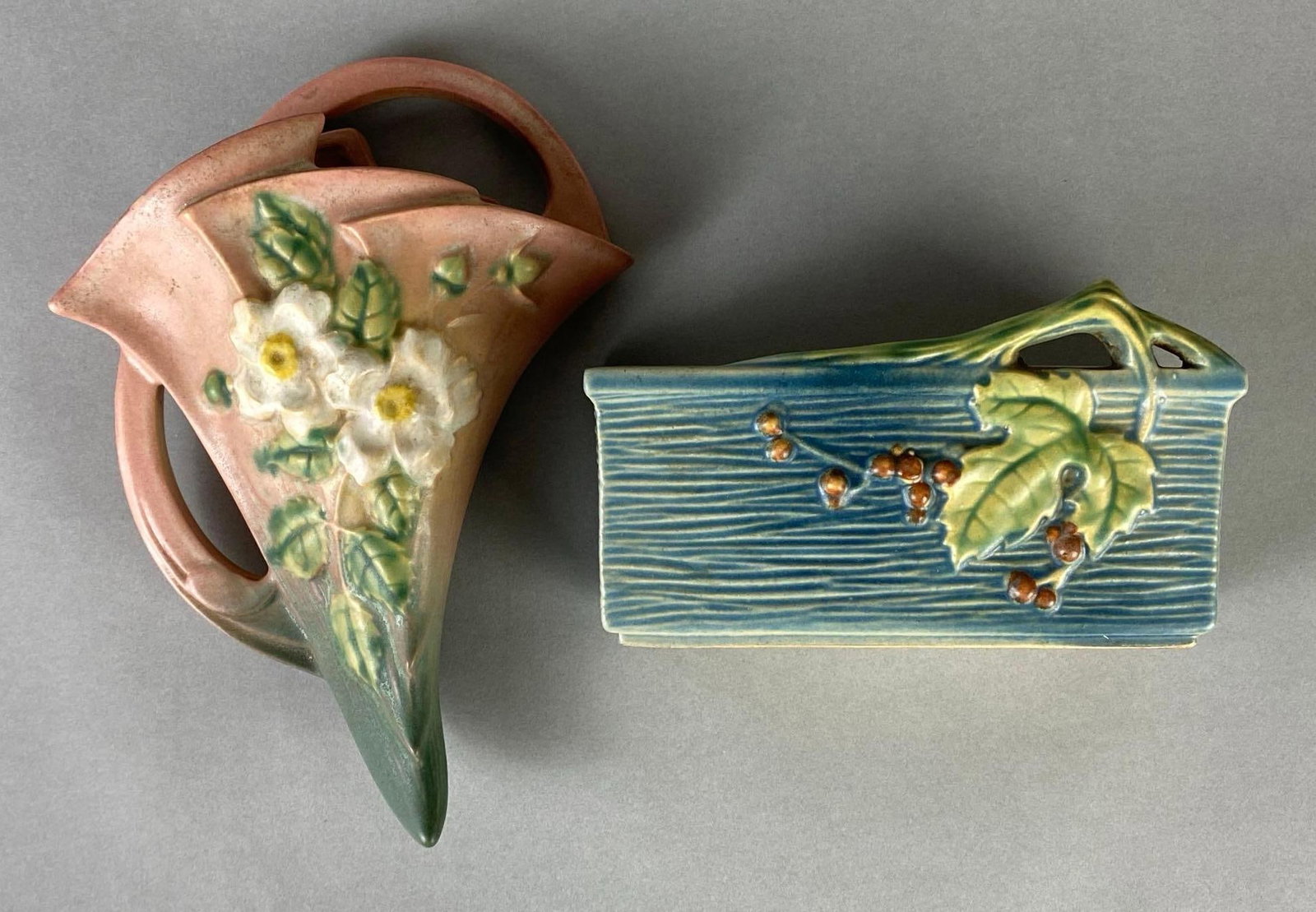 Group of 2 Roseville Pottery Items: Includes Pattern No. 1289-8 Pink/Green White Rose Wall Pocket, and Pattern No. 383-6 Blue Bushberry Planter, Wall pocket measures 9 x 6 1/2 x 2 1/2 inches.