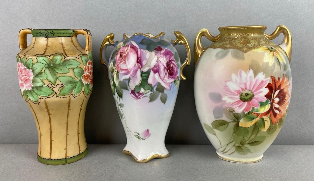 Group of 3 Nippon Hand Painted Porcelain Floral Vases: One vase has small cracks and a hole drilled on bottom and paint wear on handles. Largest measures 6 x 3 1/4 x 3 3/4 inches.