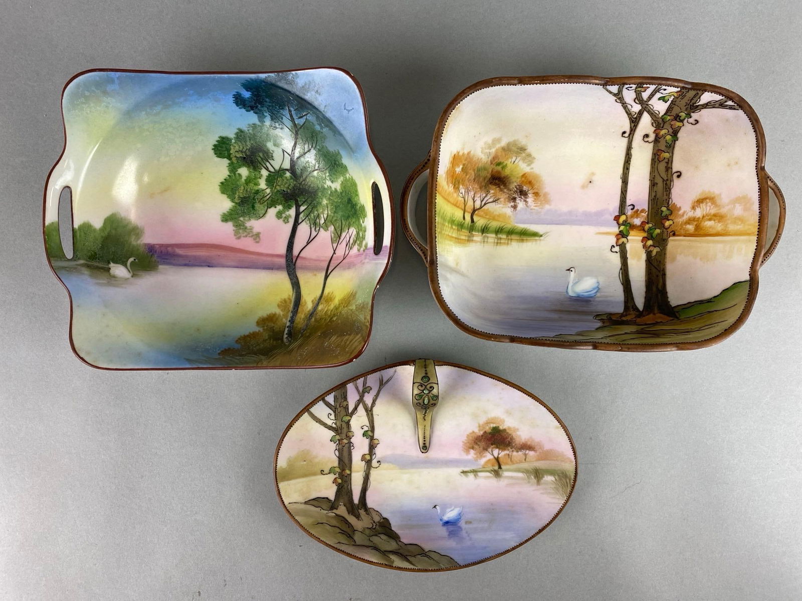 Group of 2 Nippon Hand Painted Porcelain Scenic Swan Dishes and more: Includes Noritake dish made in Japan. Two dishes have oak leafs. One dish has small chips on rim. Largest measures 2 1/4 x 5 1/2 x 8 inches.