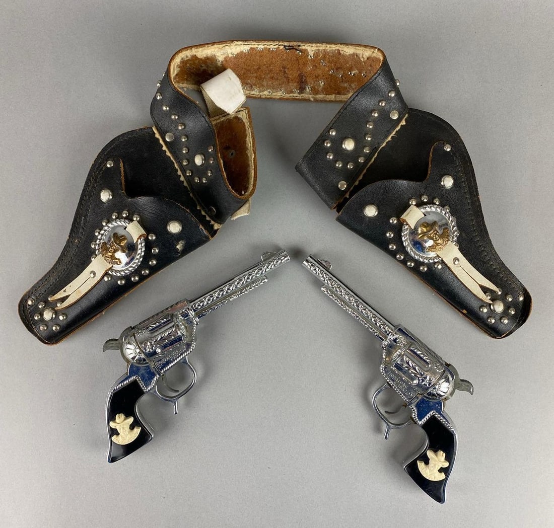 Group of 2 Hopalong Cassidy Cap Guns and Holster: Wear with age. Largest item measures 2 1/2 x 18 x 10 inches.