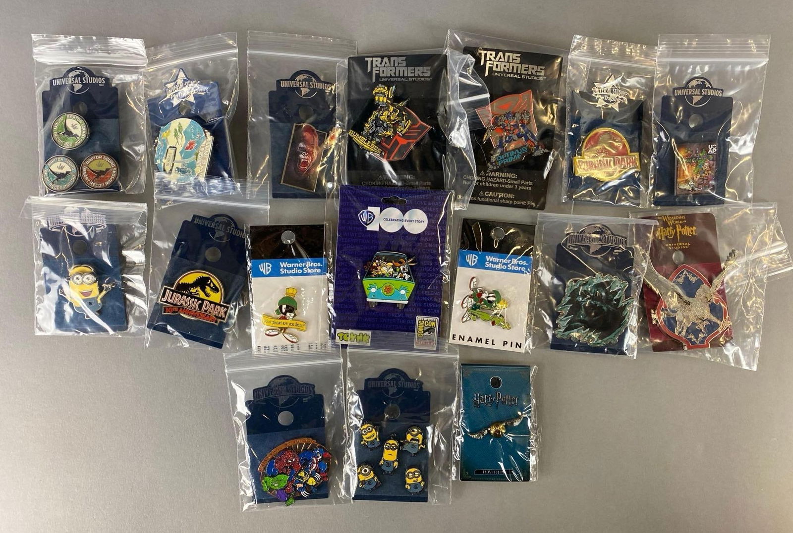 Group of 23 Warner Brothers and Universal Studio Enamel Pins: Includes Harry Potter, Jurassic Park, Minion and more. Largest pin measures 3 x 3 inches.