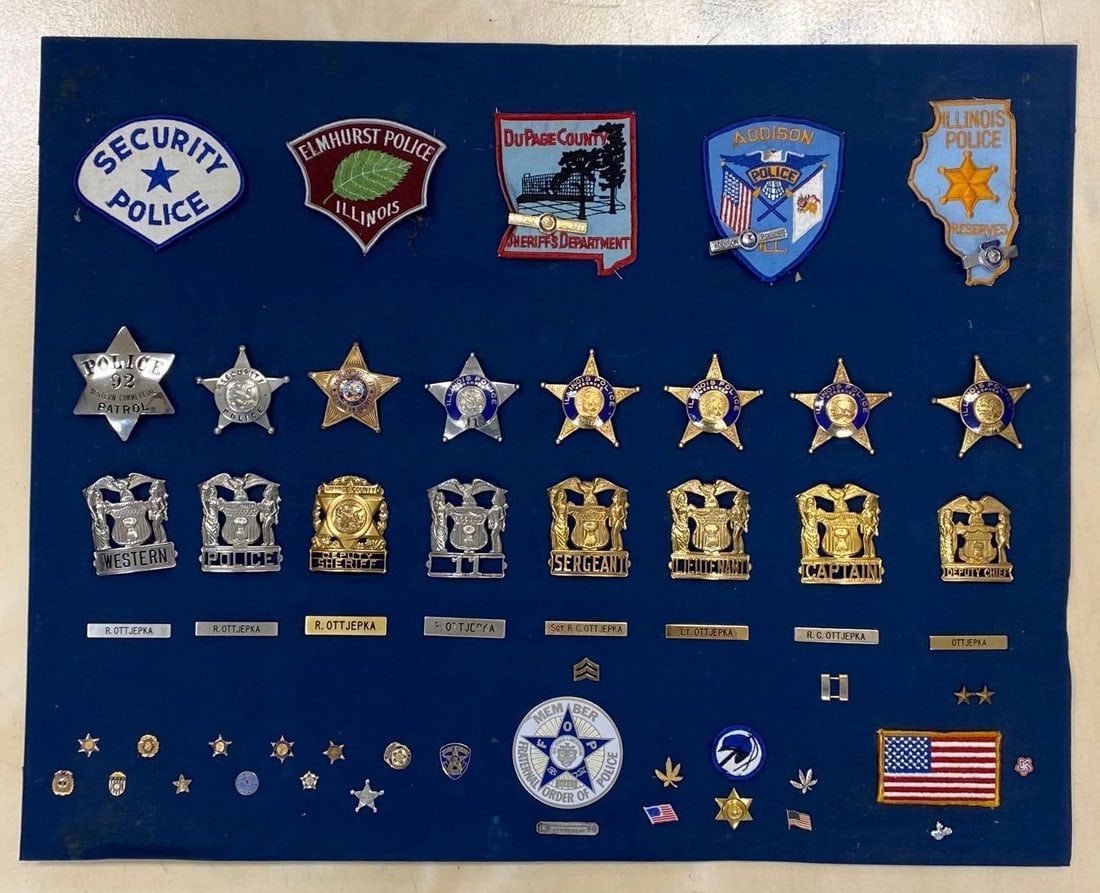Group of Illinois Police Badges and More: Most with name tag R. Ottjepka, Includes Reserves, DuPage County, Addison Police, Fraternal Order of Police, and more, Frame not attached, Backing board measures 22 1/2 x 28 1/2 inches, Frame measures