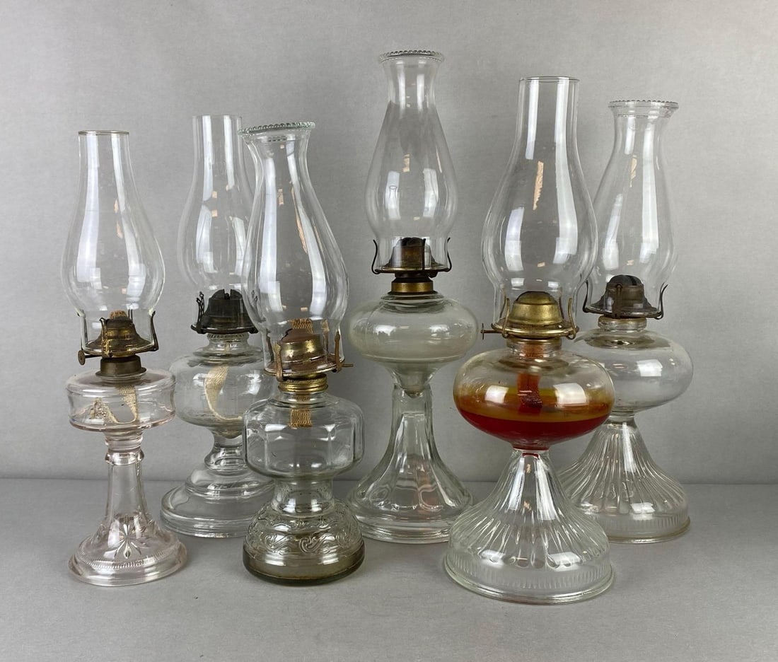 Group of 6 Clear Glass Oil Lamps: All with clear glass chimneys, Largest measures 19 1/2 x 5 1/2 x 5 1/2 inches.