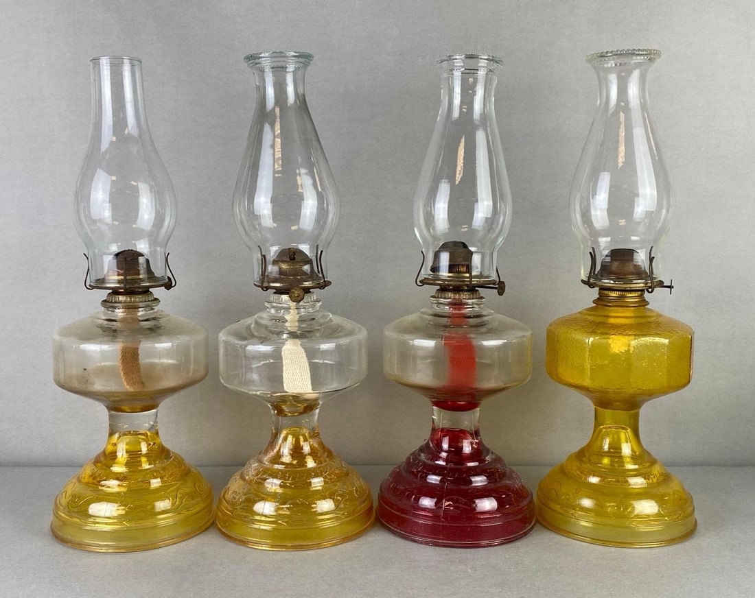 Group of 4 Clear Glass Oil Lamps with Colorized Bases: All 4 with same pattern base, One with yellow glass base and fount, Tallest measures 18 1/2 x 6 1/2 x 6 1/2 inches.