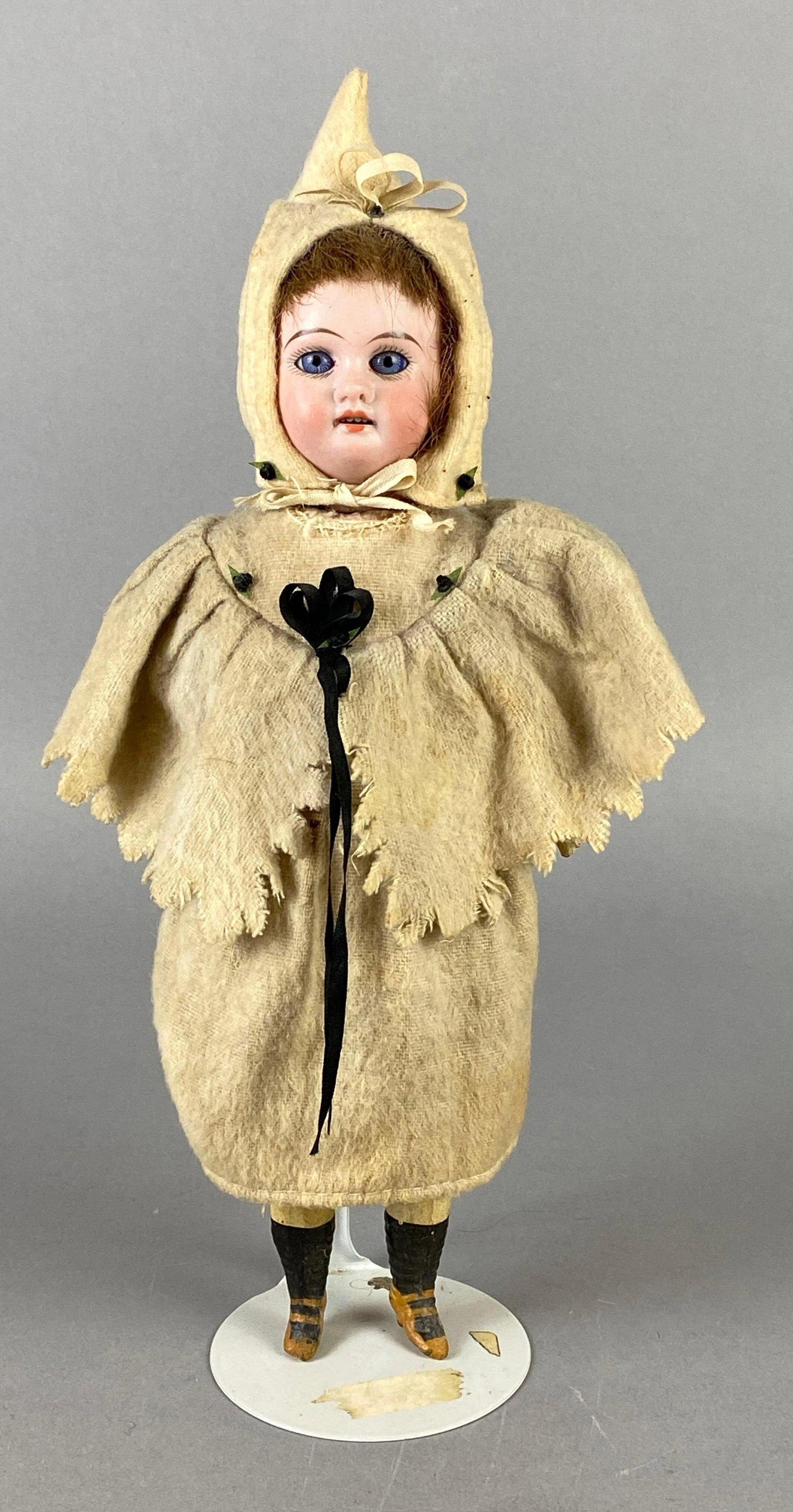 Antique German Porcelain and Composite Doll: Porcelain head with composite body, Head not fully attached, Blue eyes, Open mouth, 4 teeth, Doll stand included, Doll measures 10 1/2 inches tall.