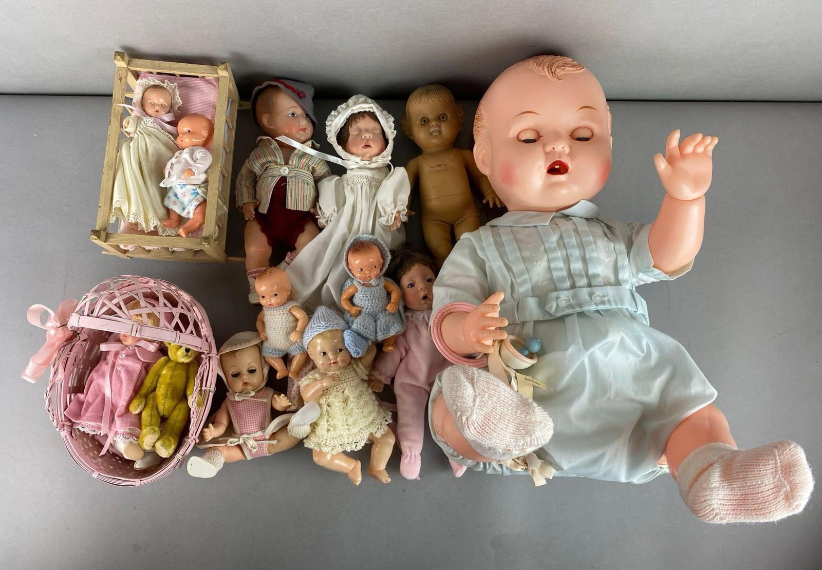 Group of 12 Baby Dolls: Features Ideal, Thumbkin, Irwin and more. Includes stuffed bear, Crib, bassinet and more. Largest doll measures 18 inches tall.