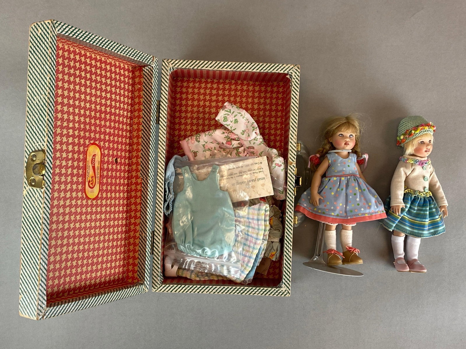Group of 2 Kish and Company Baby Dolls and Accessories: With travel case, includes dresses, sealed clothing, pairs of shoes and more, each doll measures 7 1/2 inches tall