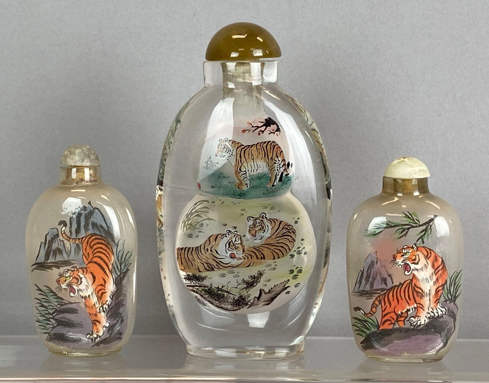 Group of 3 Chinese ROG Tiger Snuff Bottles: Reverse on glass, Cap on one bottle not attached, Largest measures 5 x 2 1/2 x 1 1/2 inches