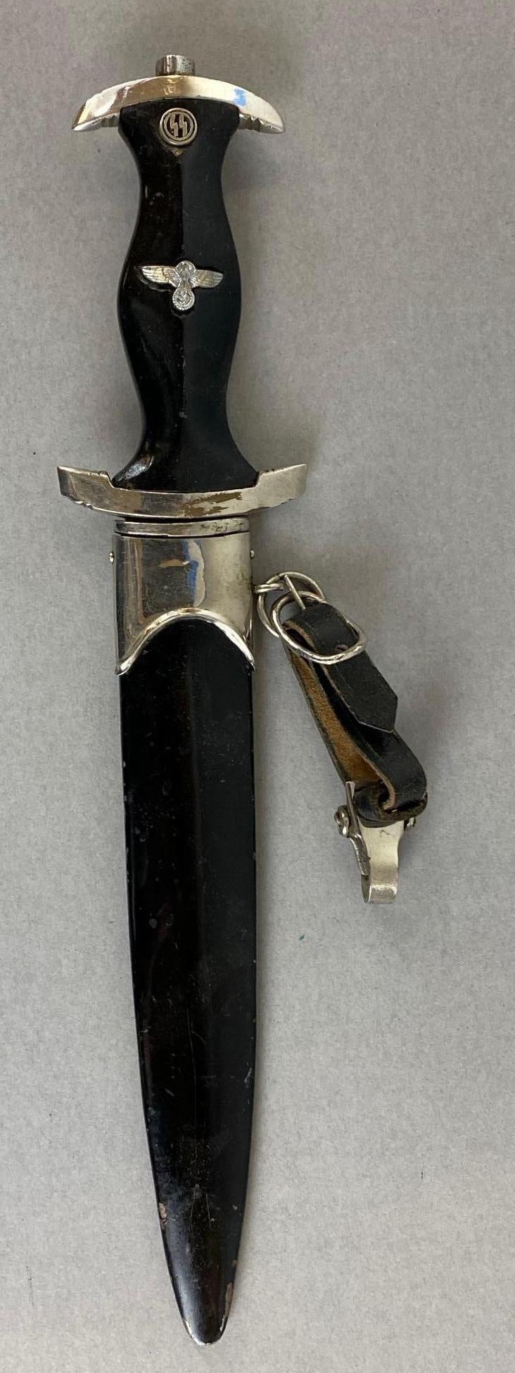 Reproduction German SS Dagger with Scabbard and Hanger: Blade inscribed Meine Ehre Heißt Treue on one side. Other side marked RZM 121/38 SS. Scabbard is scratched up. Dagger measures 13 1/4 inches. Blade measures 8 1/4 inches.