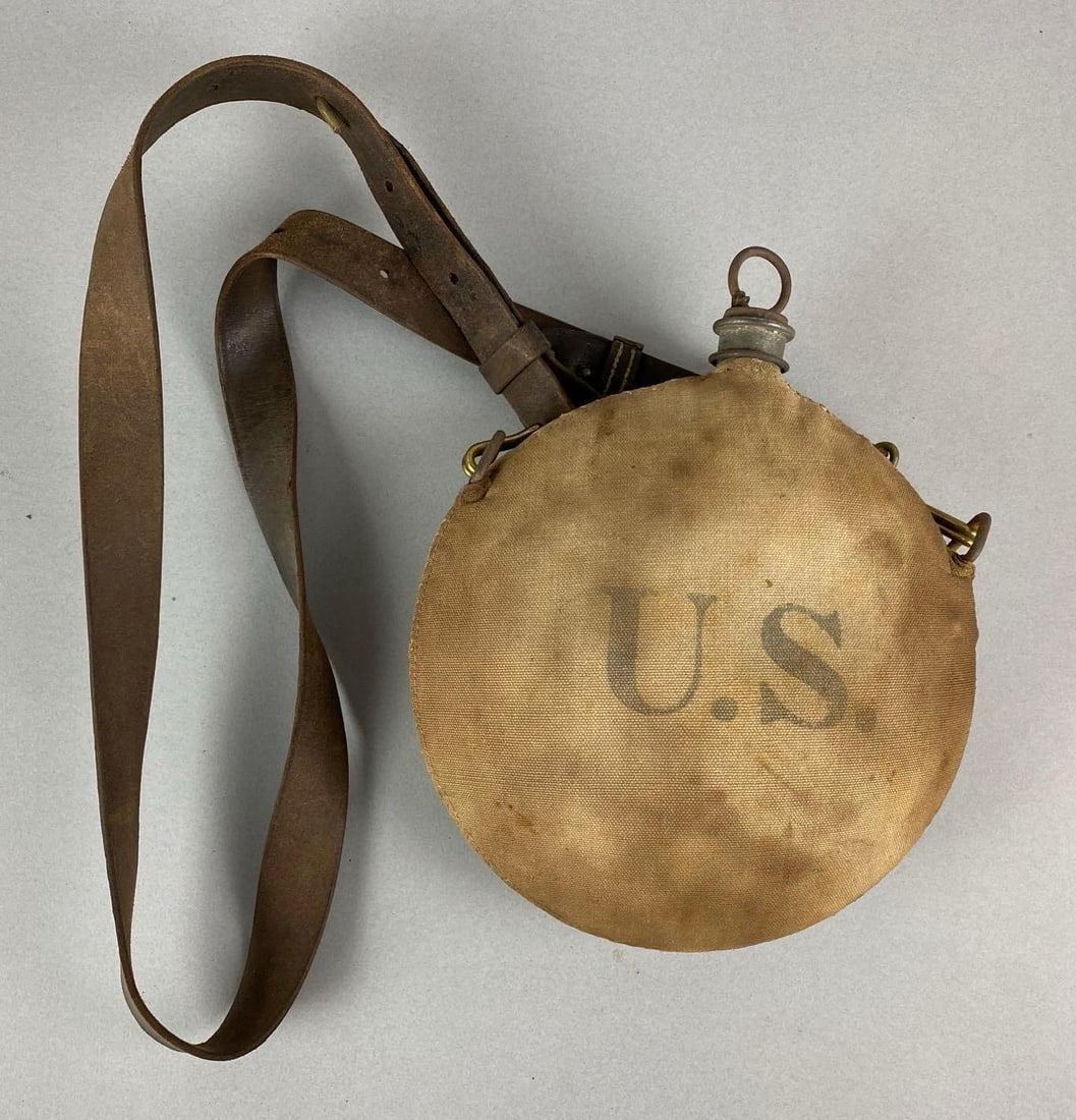 Spanish American War Canteen and Shoulder Strap: Staining and corrosion spots. Canteen measures 10 x 8 x 3 inches.