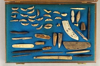 Frame of fishing implements from Alaska; includes several harpoons, some pieces made from ivory