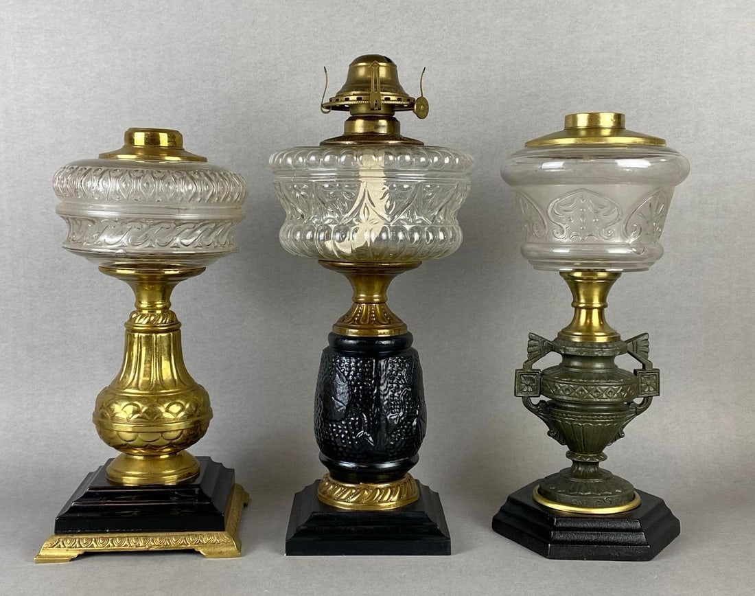 Group of 3 Cast Metal Oil Lamp Bases: All with Clear embossed glass founts, Tallest measures 15 x 6 1/4 x 6 1/4 inches.