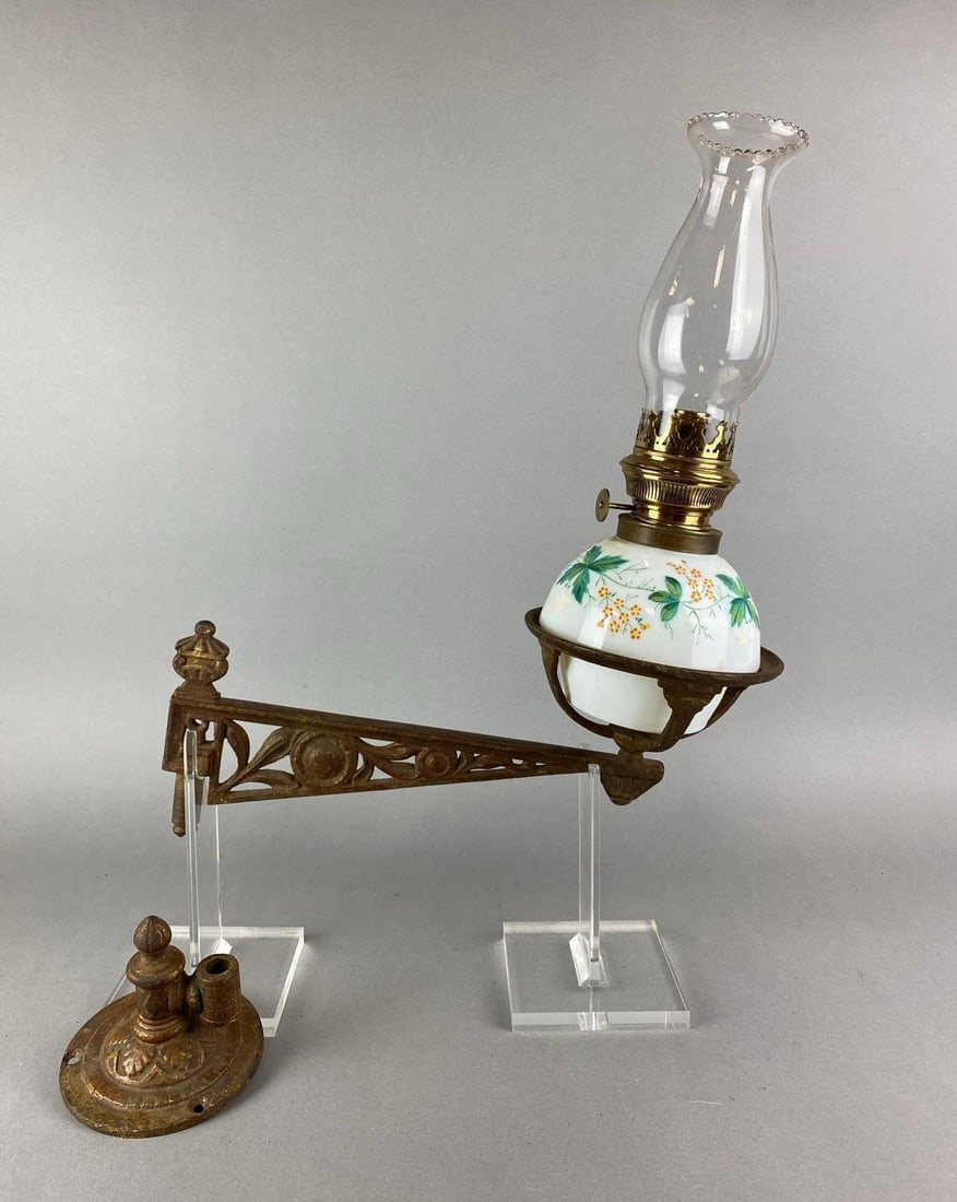 Antique Cast Iron Oil Lamp Wall Sconce: Includes oil lamp with hand painted floral motif. Sconce has rust. Oil lamp measures 13 1/4 x 7 x 7 inches. Sconce measures 6 x 6 x 14 inches.