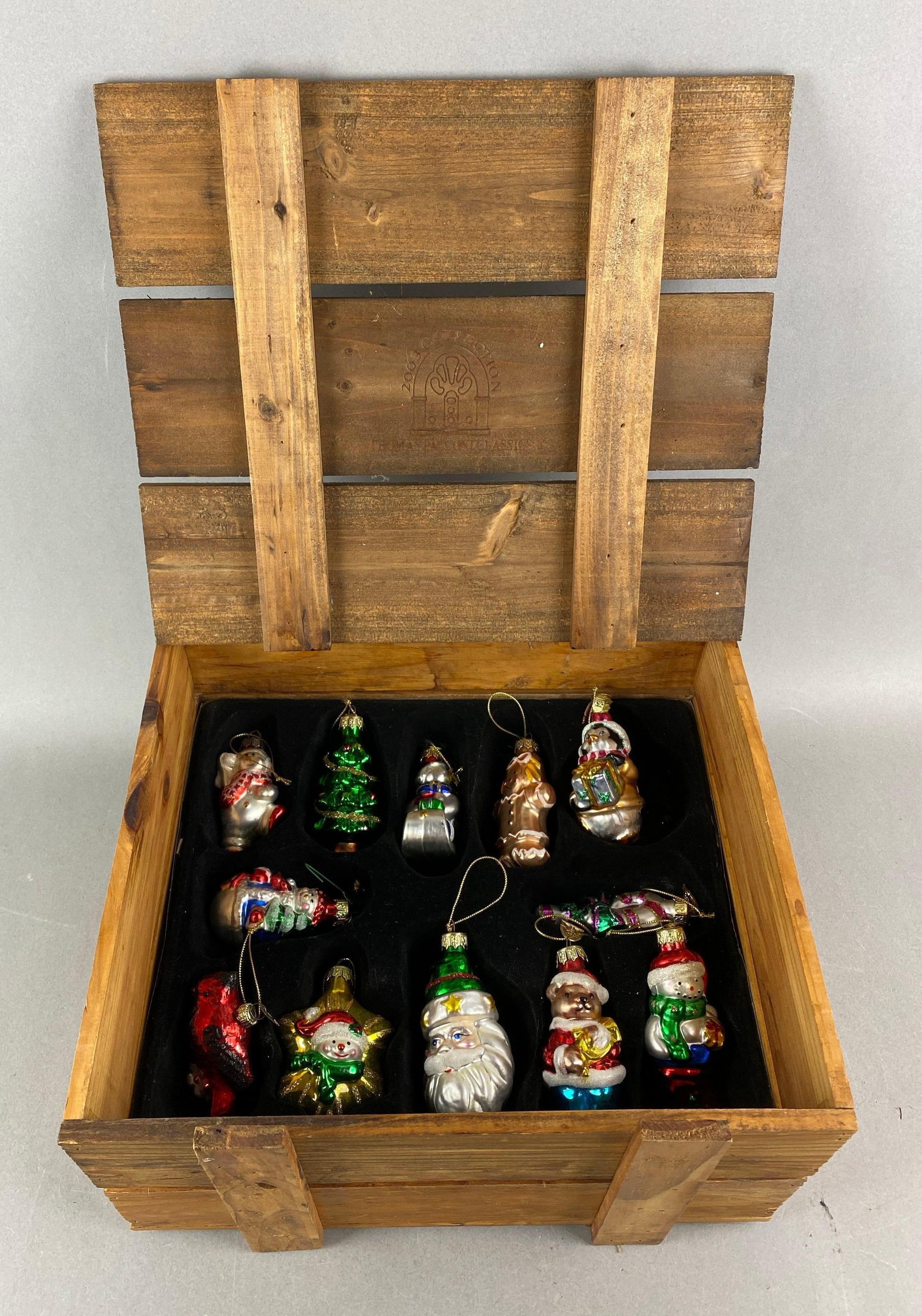 Group of 12 Thomas Pacconi Classics Blown Glass Christmas Ornaments: Includes Santa, gingerbread woman and more. Crate measures H 7 1/4 x W 12 1/2 x D 11 3/4 inches.