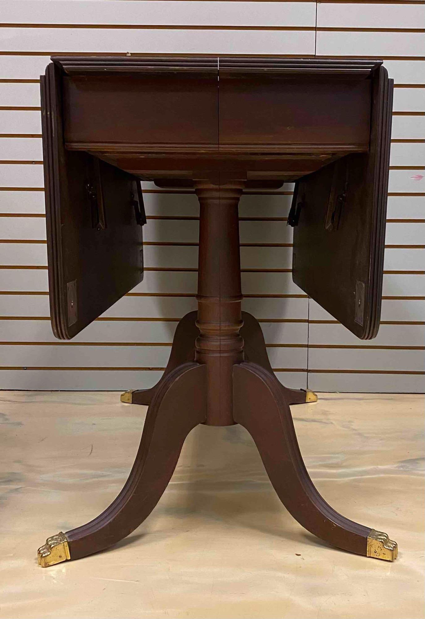 Duncan Phyfe Style Mahogany Drop Leaf Table: Brass Claw Feet. Measure L 48 x W 40 inches when extended. Comes with vinyl top table mat. No in house shipping. Third party shipping recommended.