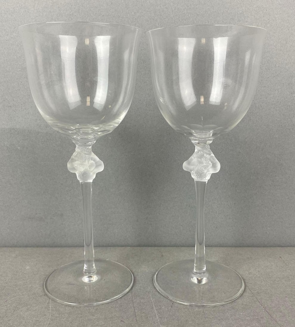 Group of 2 Lalique Roxane Crystal Wine Glasses: One has a small chip on the rim. Both are marked on the bottom. Largest measures H7 x W3 x D3 inches.
