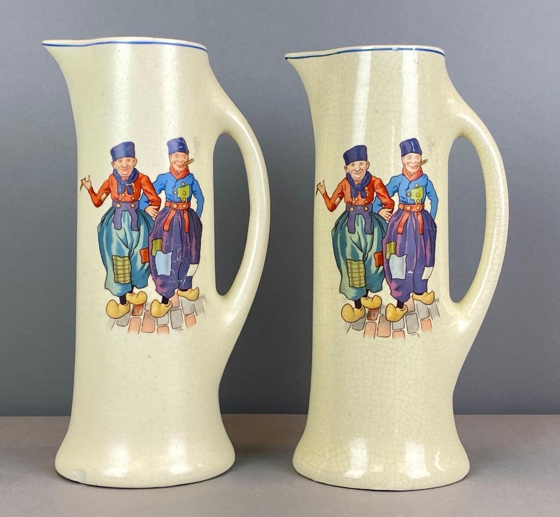 Group of 2 Vintage Roseville Pottery Dutchmen Pitchers: Chip on one base, each measures 11 1/2” H x 6 1/2” W x 5” D