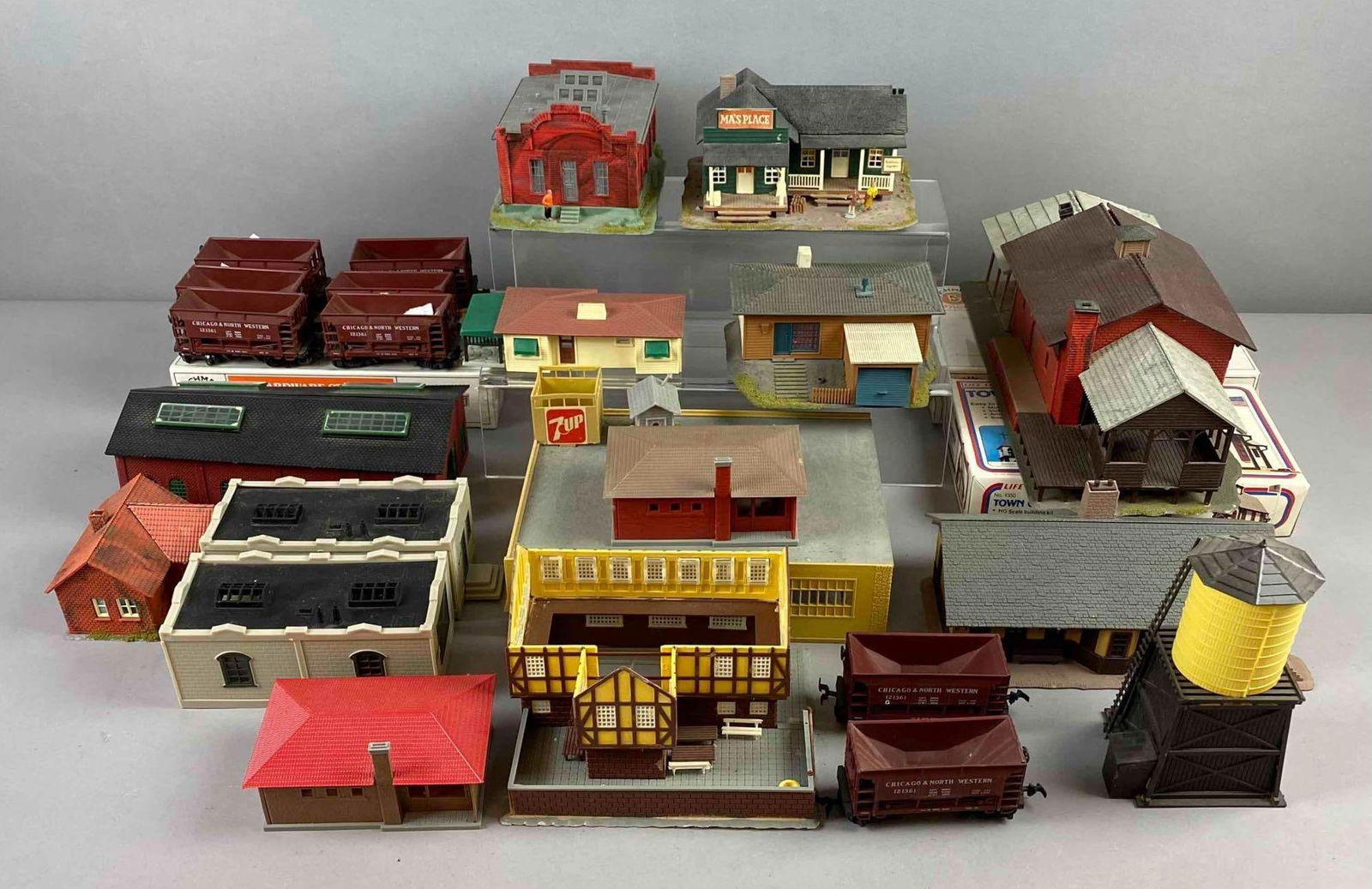 Group of Assorted HO Scale Model Buildings and More: Includes HO scale Chicago & North Western Ore cars, 7 up building, and more. Largest measures H 4 x W 6 x L 12 1/2 inches. Some small pieces may be missing. Various conditions throughout.