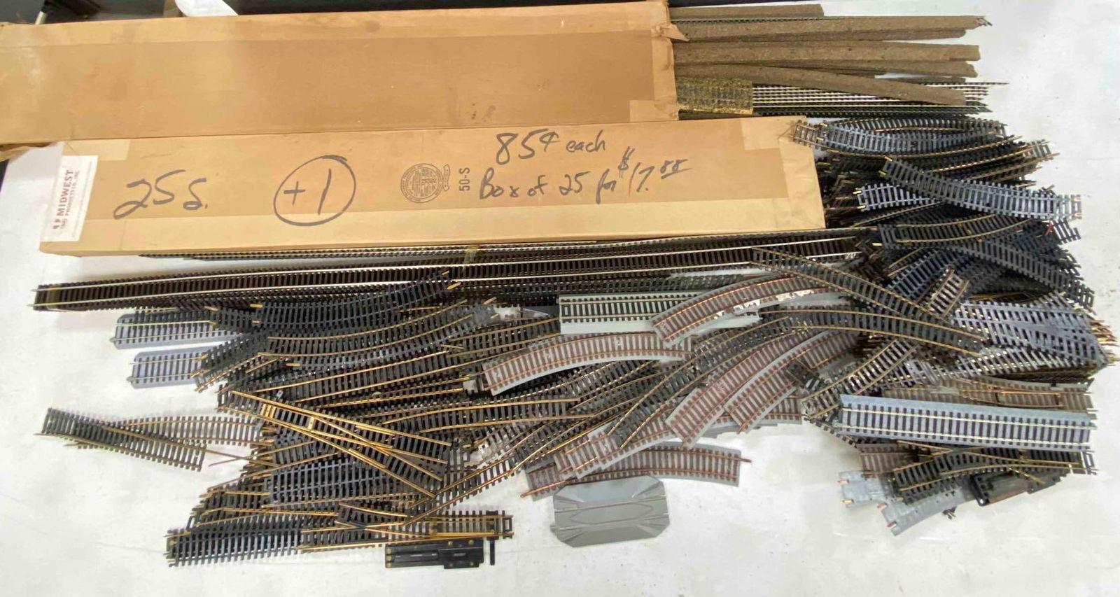 Group of 50 + Altas HO Scale Tracks and More: Various sizes. Includes Midwest rails and cork boxes, switches, curve, straight, and more. Box measures H 2 x W 6 x L 37 inches.