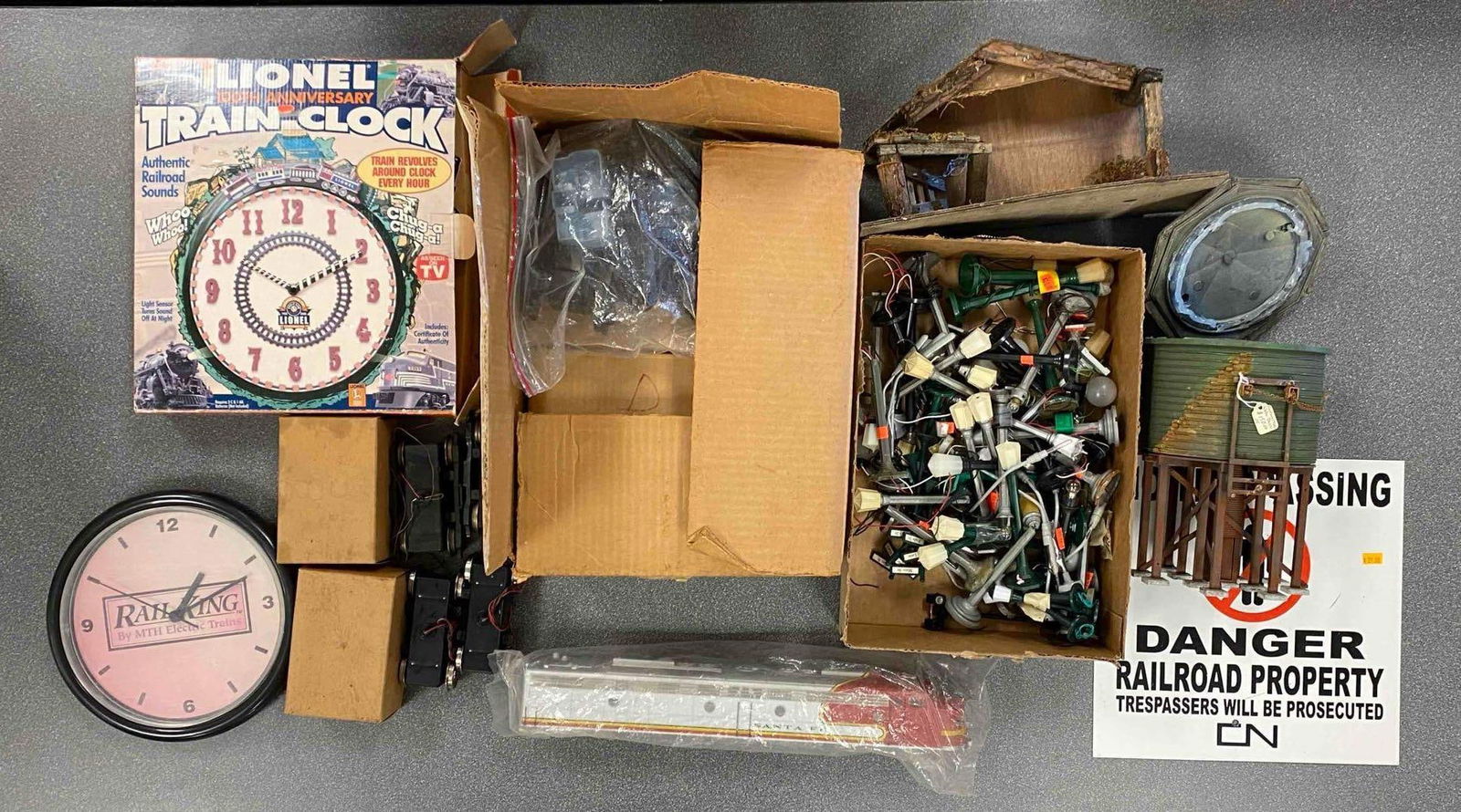Group of Assorted Model Train Accessories and More: Includes rail king analog clock, no trespassing sign, street lights and more, largest box measures 13” H x 13” W