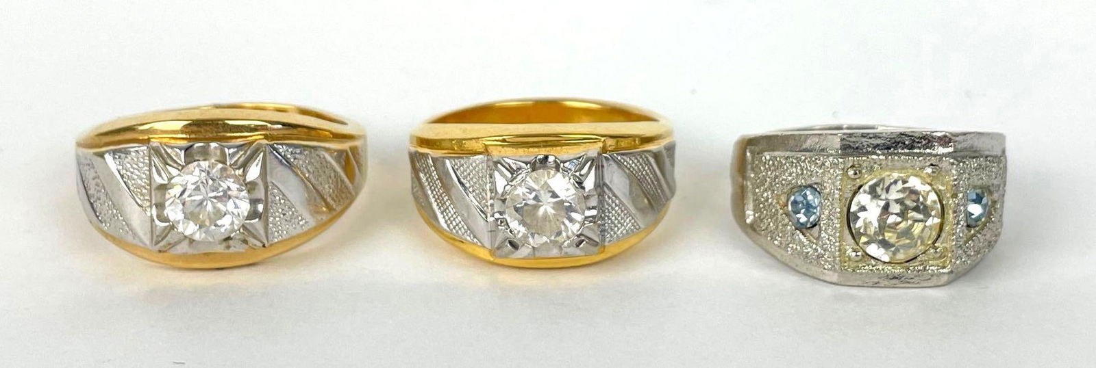 Group of 2 14K Gold Plated and Sterling Silver CZ Rings: Both marked HGE, one signed Lind, silver color ring with glass insets, sizes 11-13, 2 gold rings are 23.7g combined weight