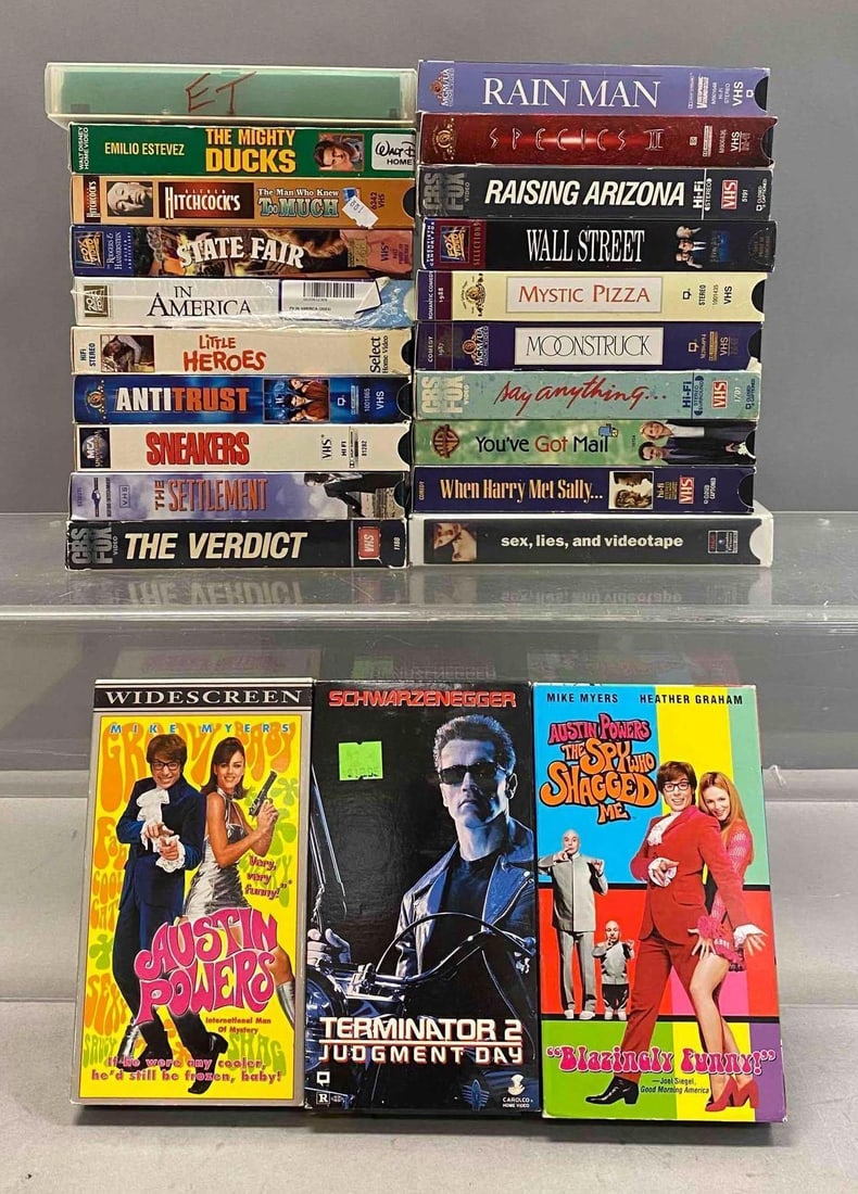 Group of Assorted VHS Tapes: Includes Hit Classics such as Terminator 2 Judgment Day, Austin Powers 1 and 2, and more. One tape measure L 7 1/2 x W 4 inches. Stand not included.