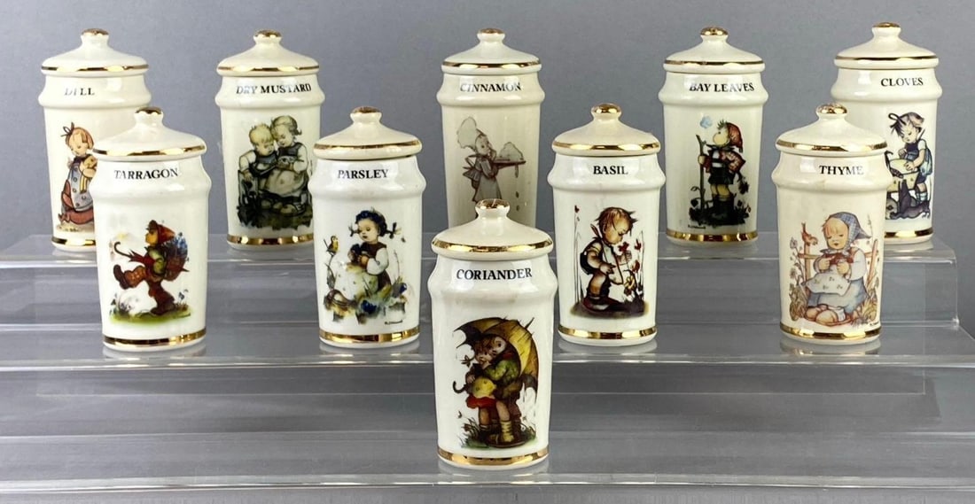 Group of 10 1987 M.J. Hummel Porcelain Spice Jars: Made in Japan. Some have tape residue and cracks in jar. One measures 4? in length. Stand not included.