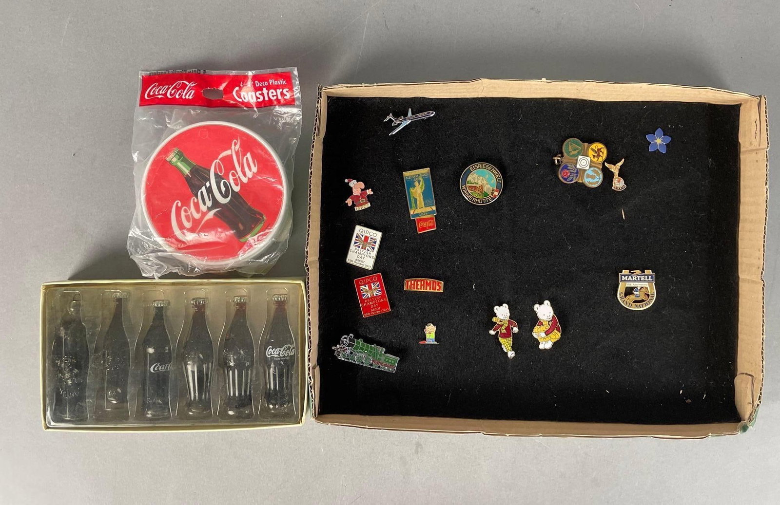 Group of Enamel Pins and Coca-Cola Advertising Items: Includes coasters, miniature bottle packaging measures 4" x 7" x 1"